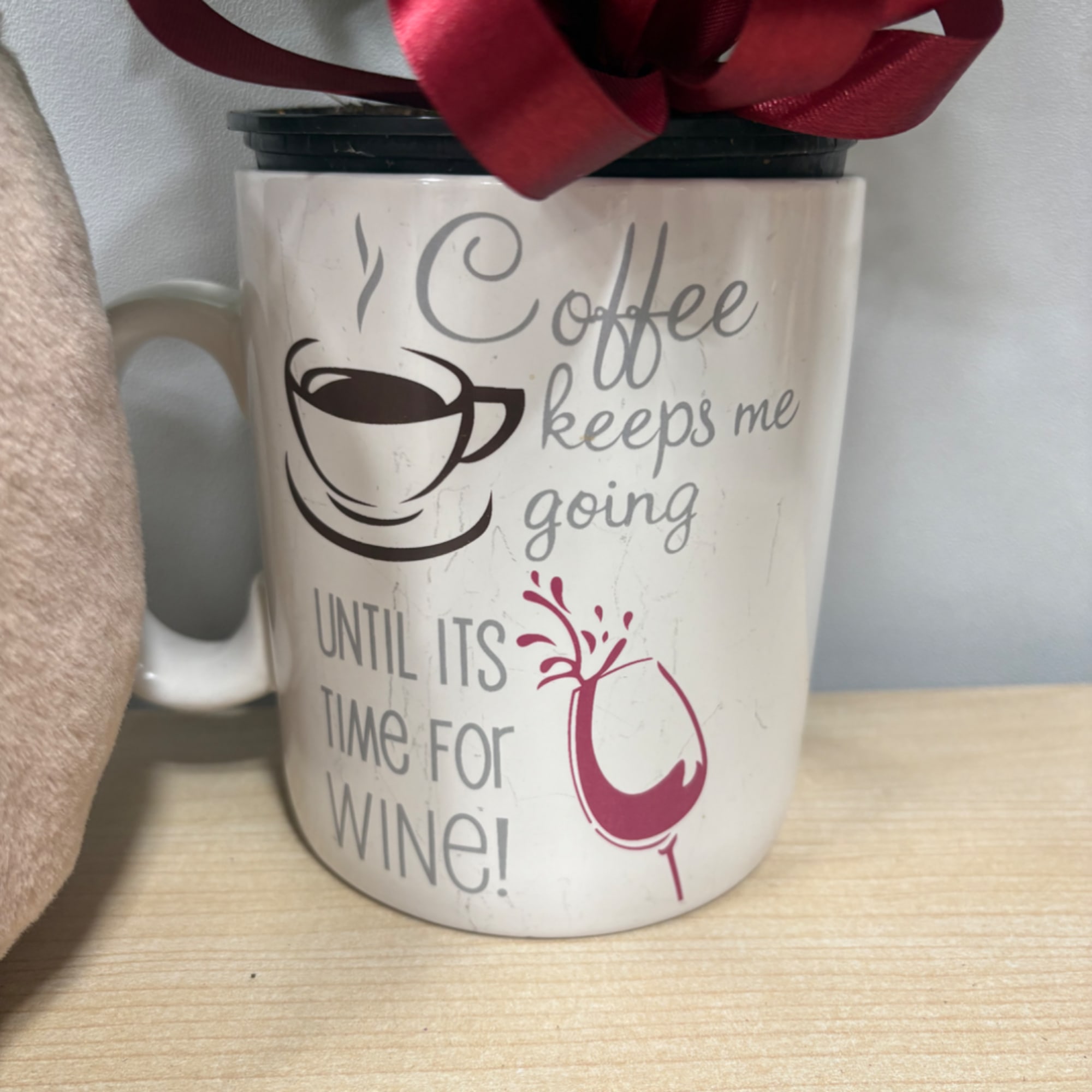 Coffee mug with a wine-themed quote and a red ribbon bow on top