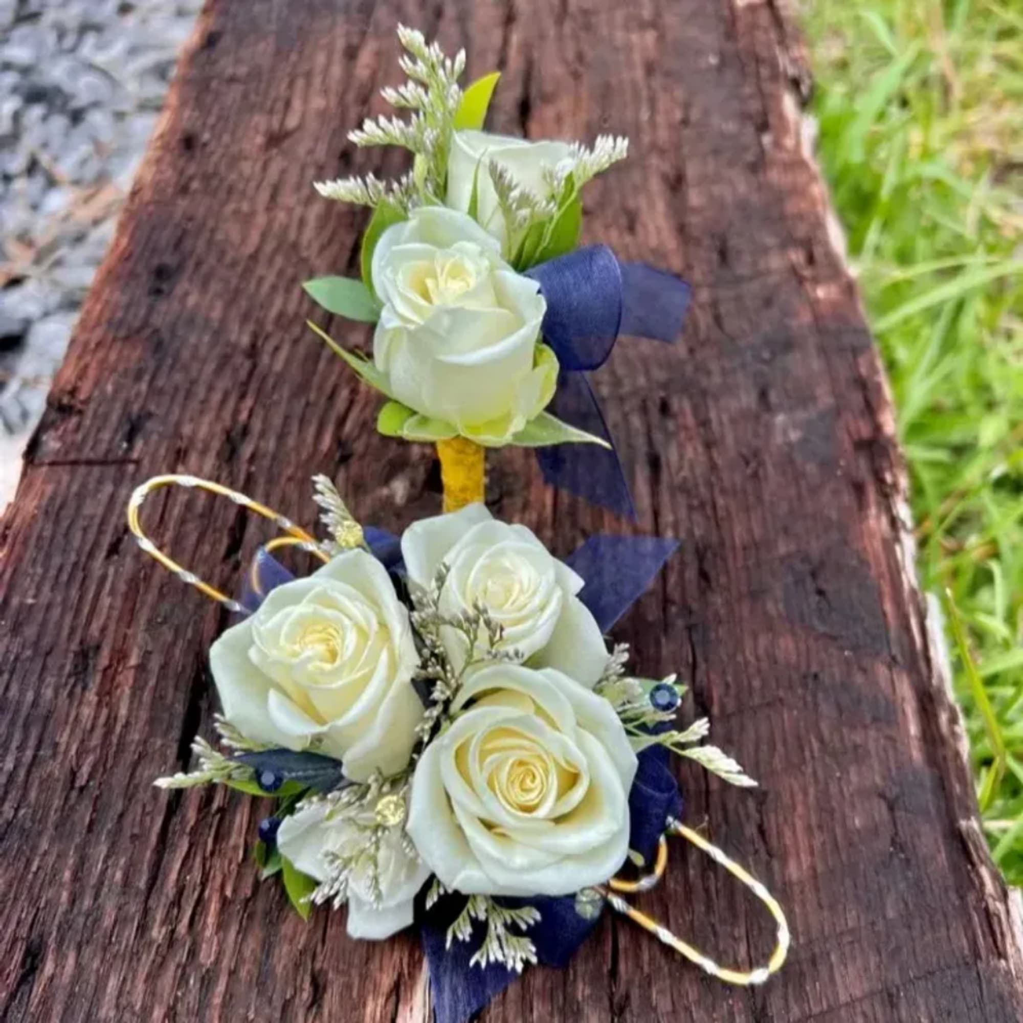 White rose corsage with blue ribbon accents on a wooden surface