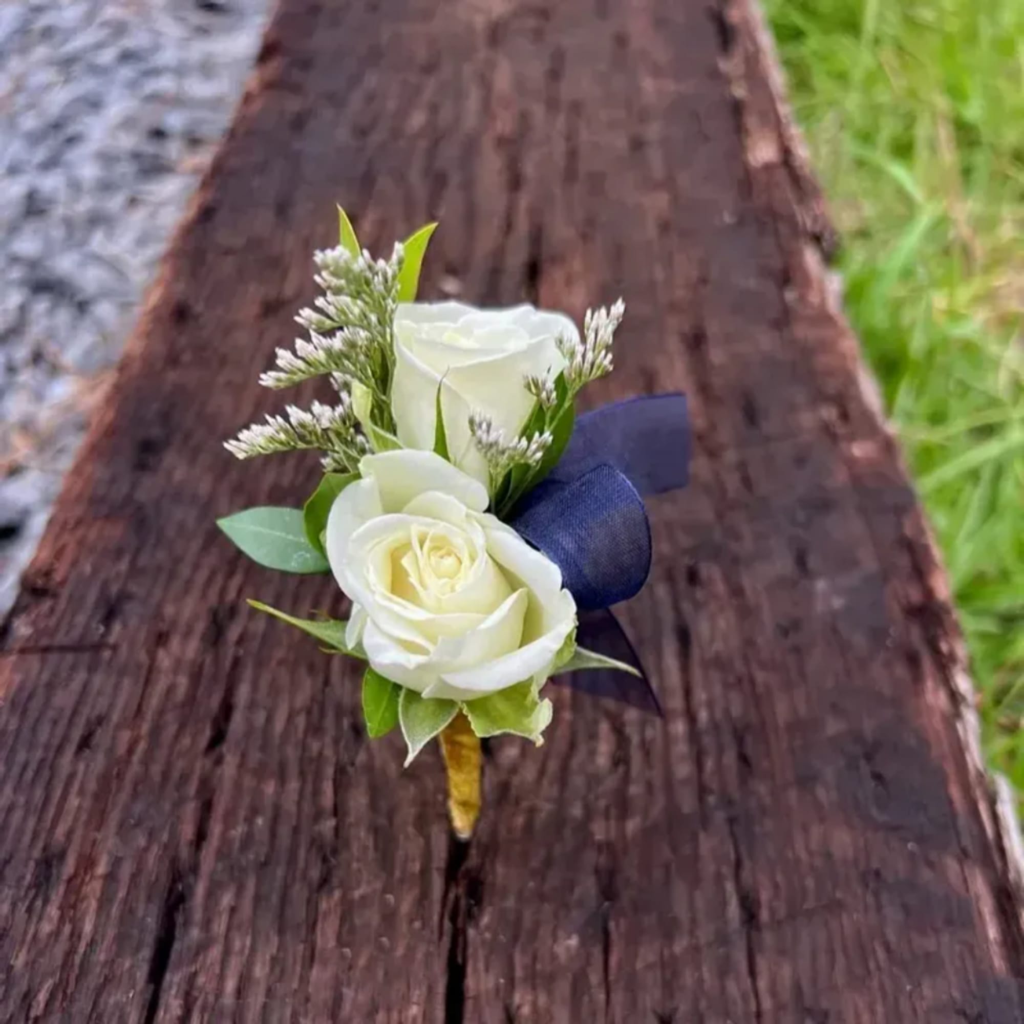 White rose boutonniere with navy ribbon on a wooden surface, photo 3 of 3