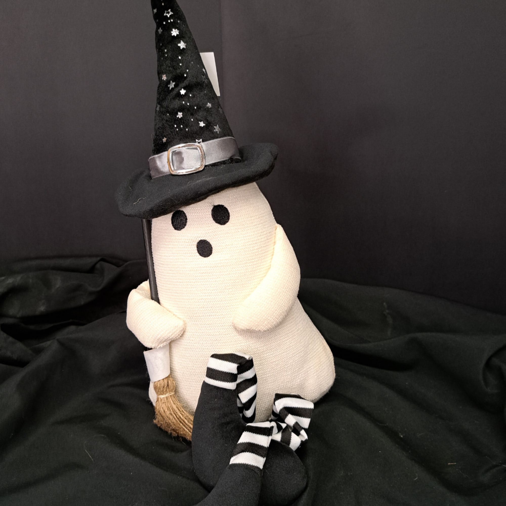 Plush ghost decoration wearing a witch hat and holding a broom