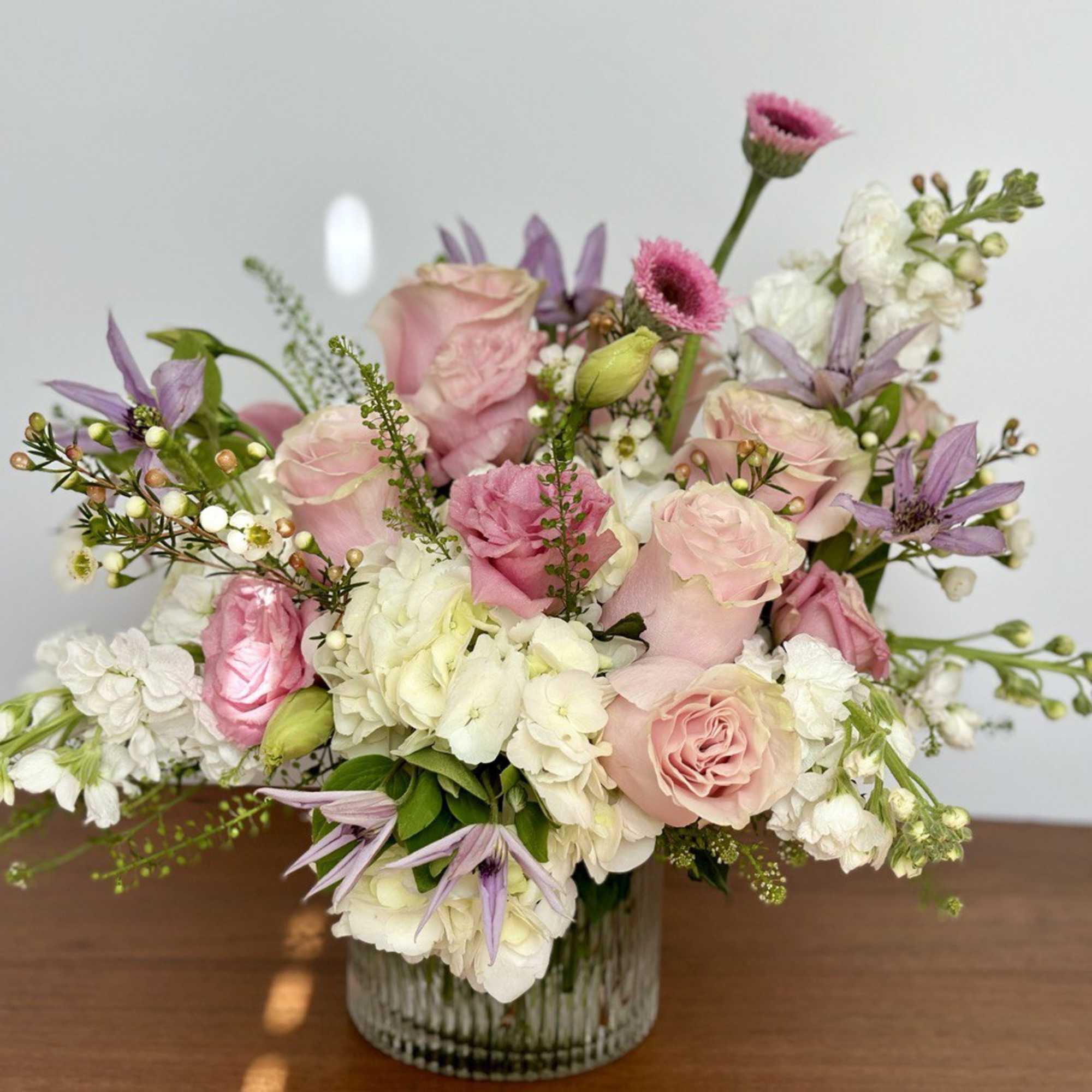 Pink and white flower arrangement in a ribbed glass vase