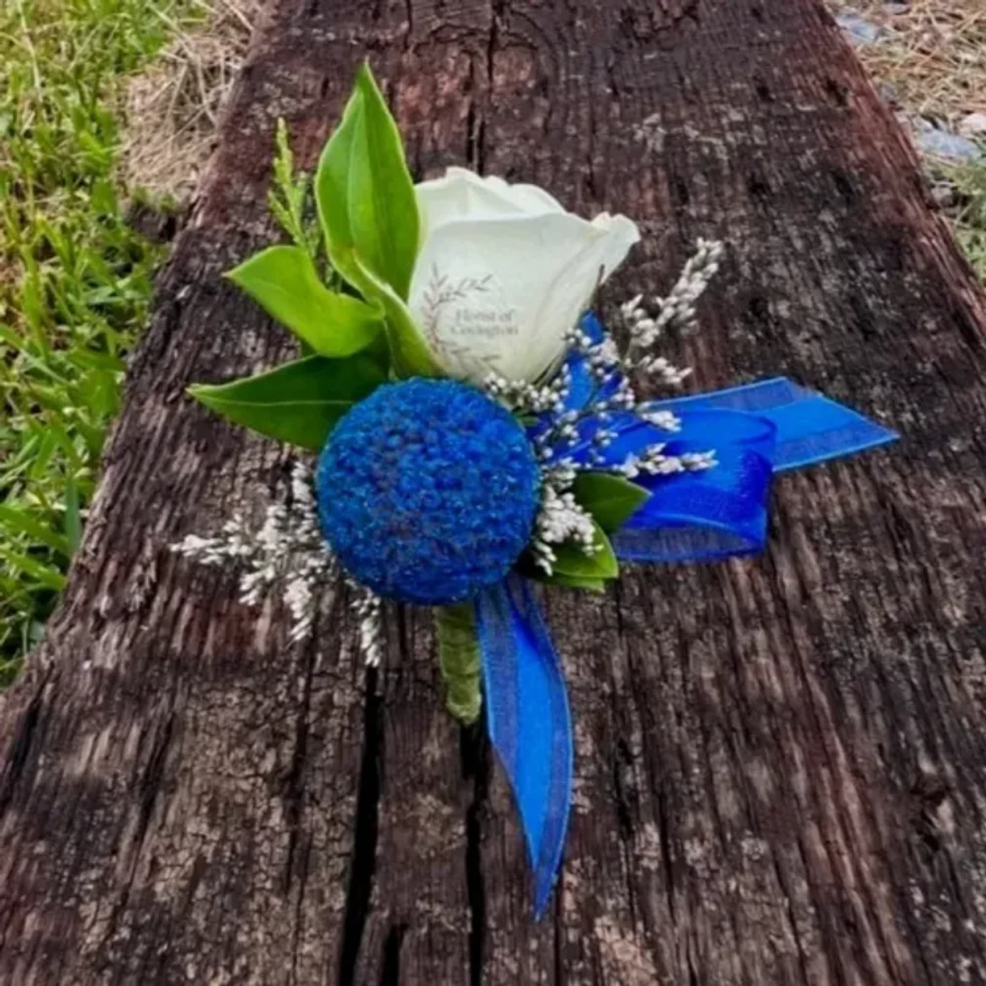 Blue and white boutonniere with ribbon on a wooden surface