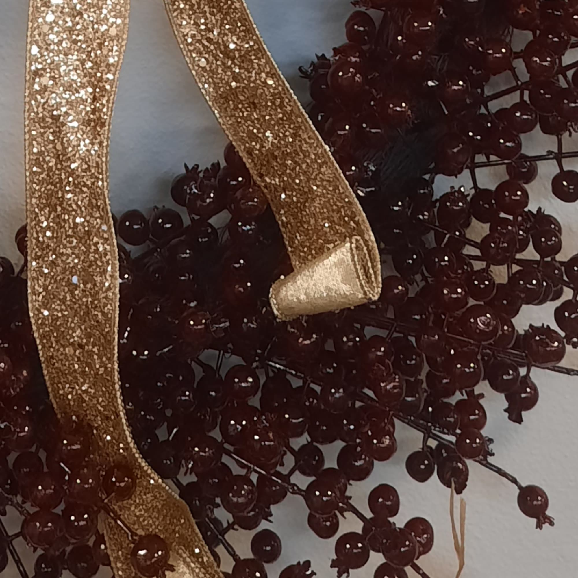 Glittery gold ribbon over dark red berry stems