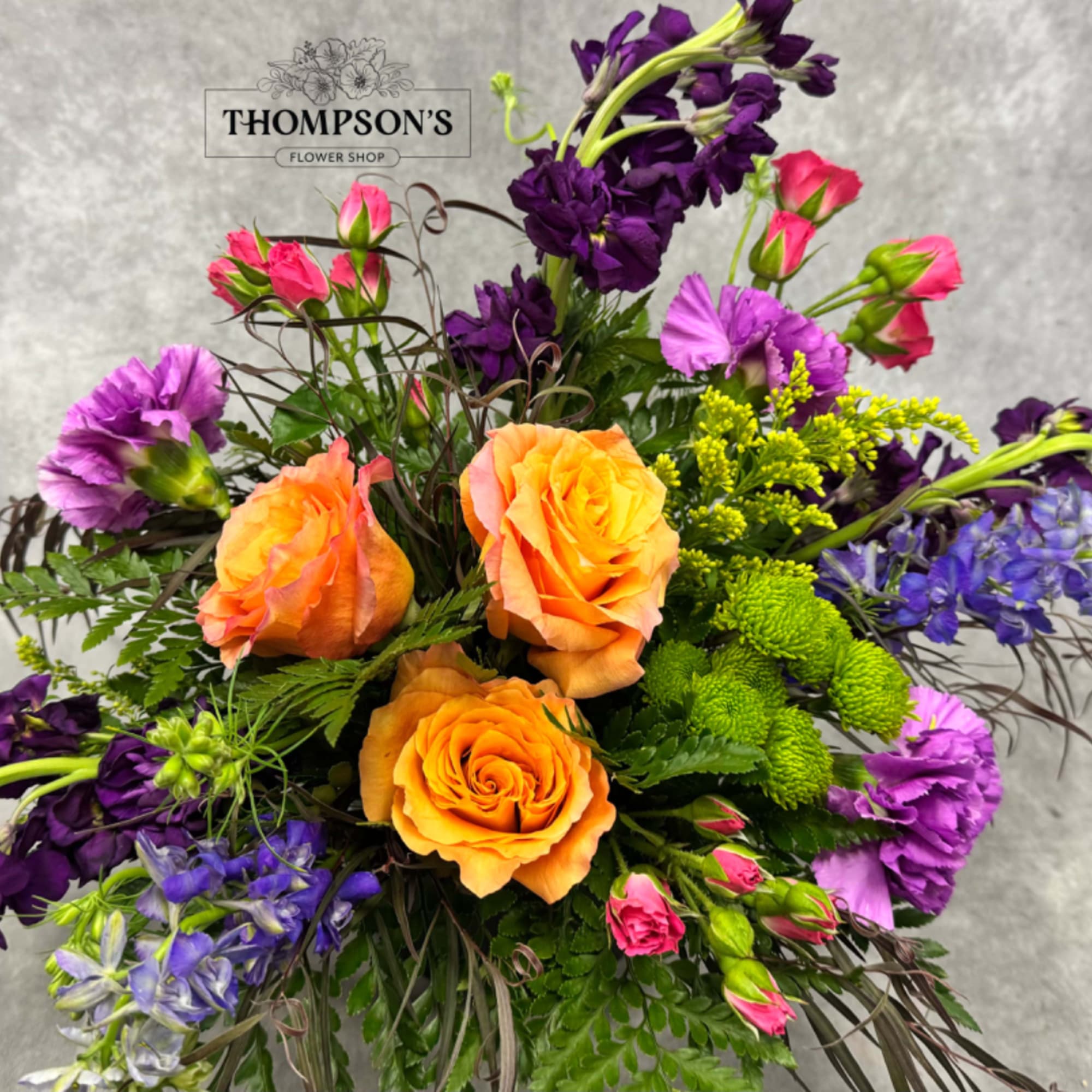 Colorful bouquet with orange roses, purple flowers, and pink spray roses