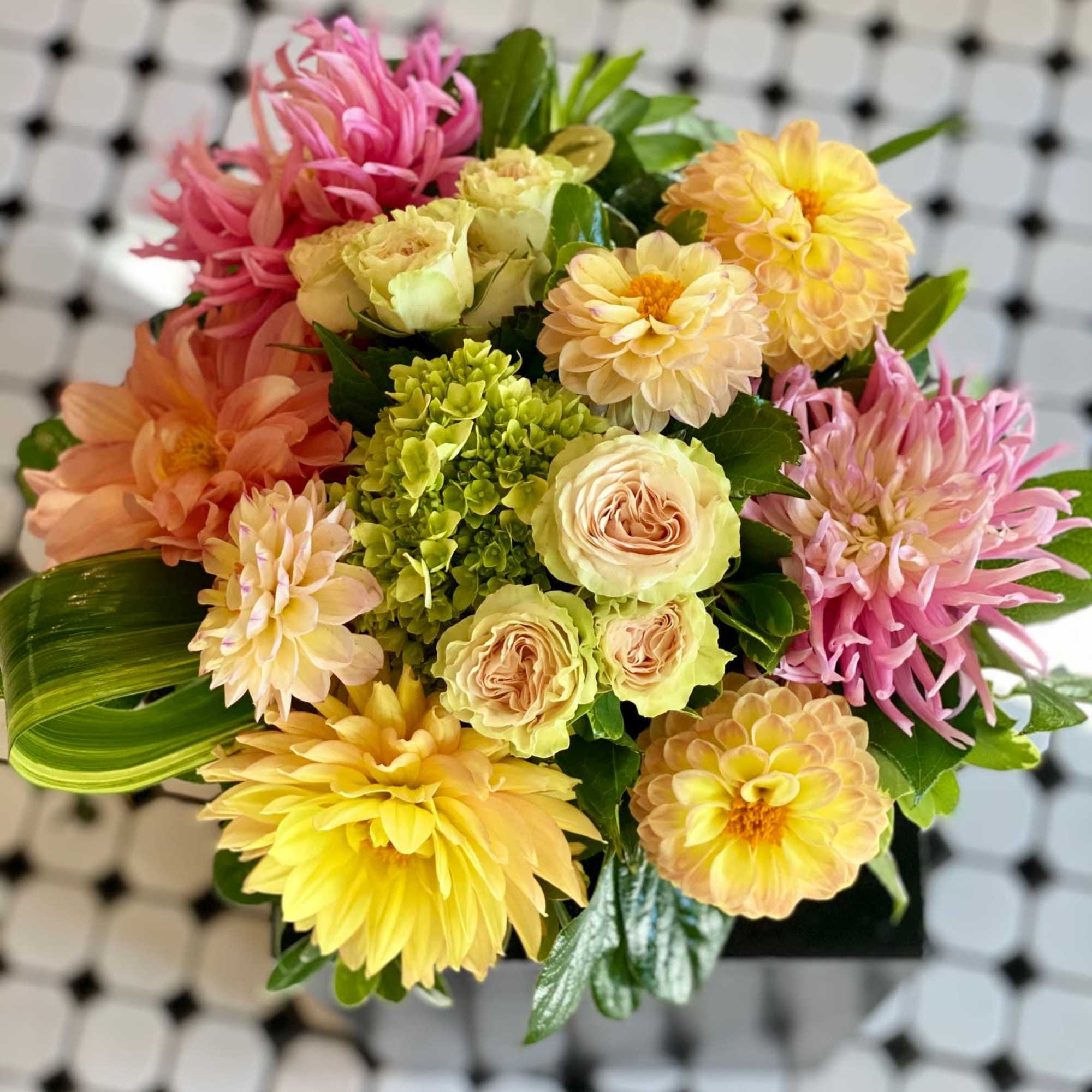 Mixed bouquet of pink, yellow, and peach flowers in a compact arrangement