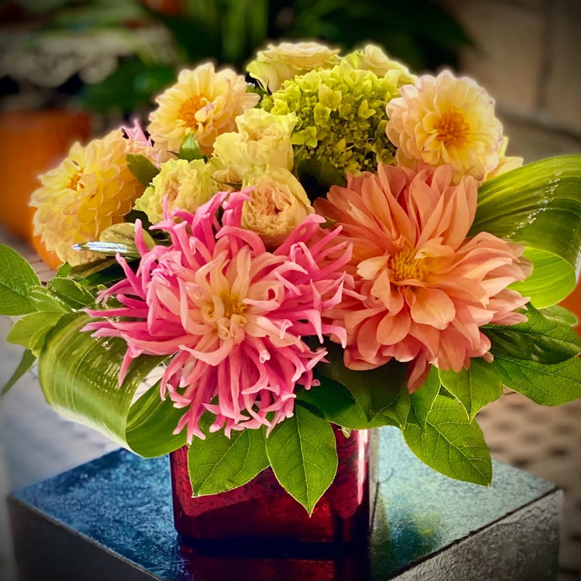 Colorful mixed bouquet in a red glass vase with pink and peach blooms