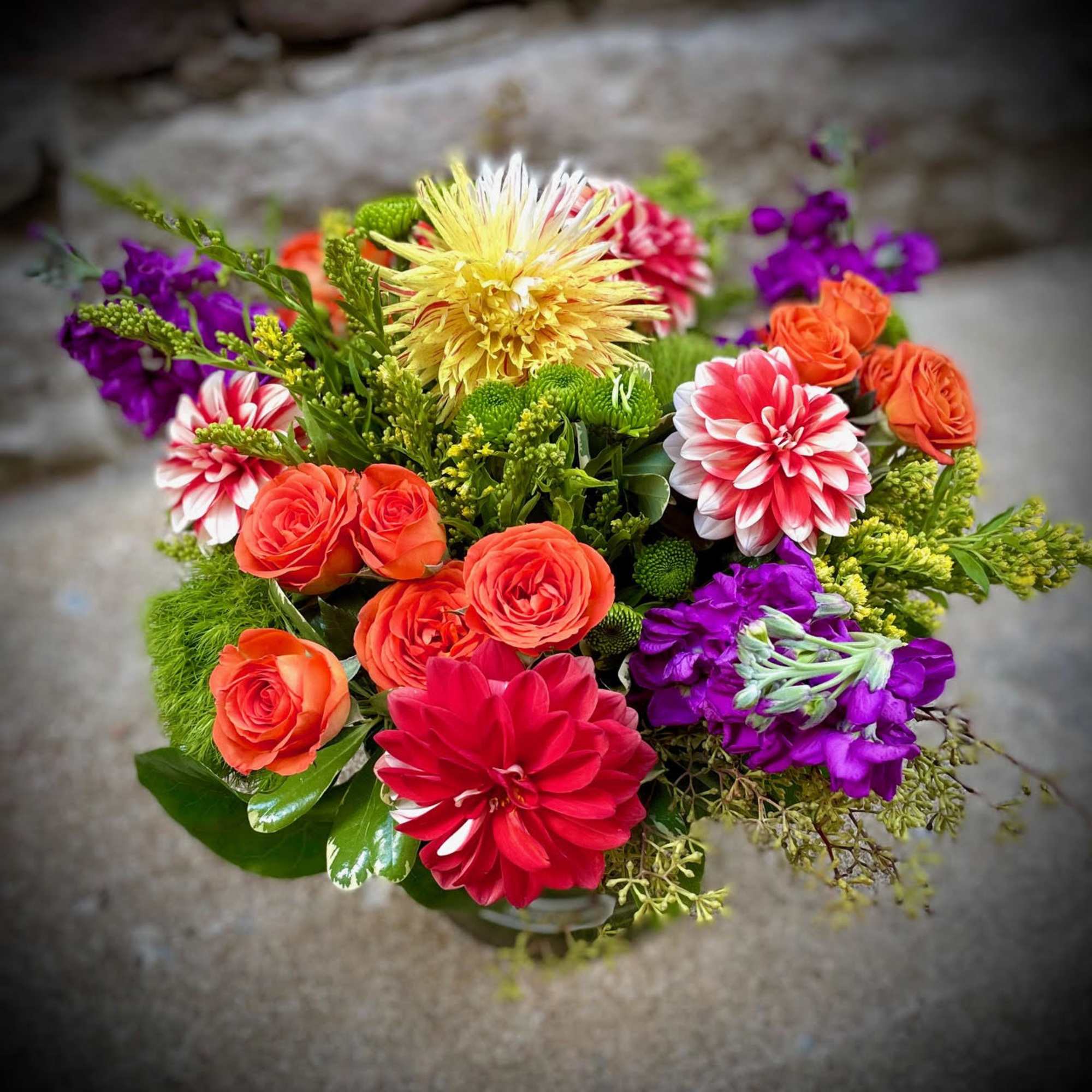 Colorful bouquet with orange roses, purple blooms, and red-and-white dahlias