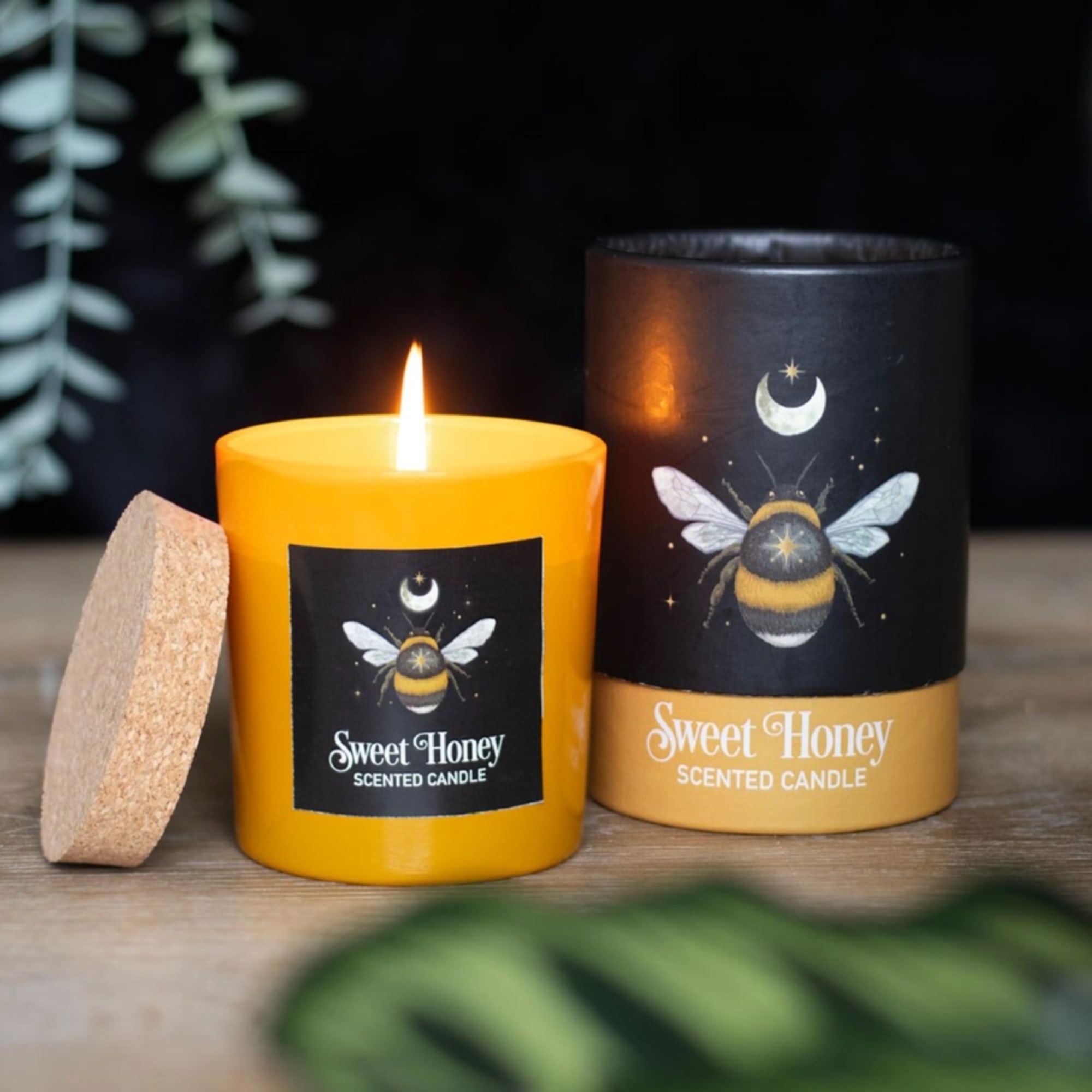 Two sweet honey scented candles, one lit, with bee labels
