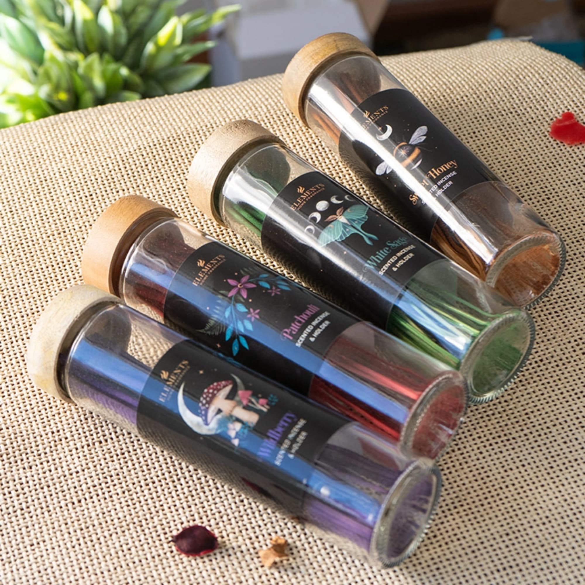Four glass tubes with wooden lids holding assorted dried flower petals