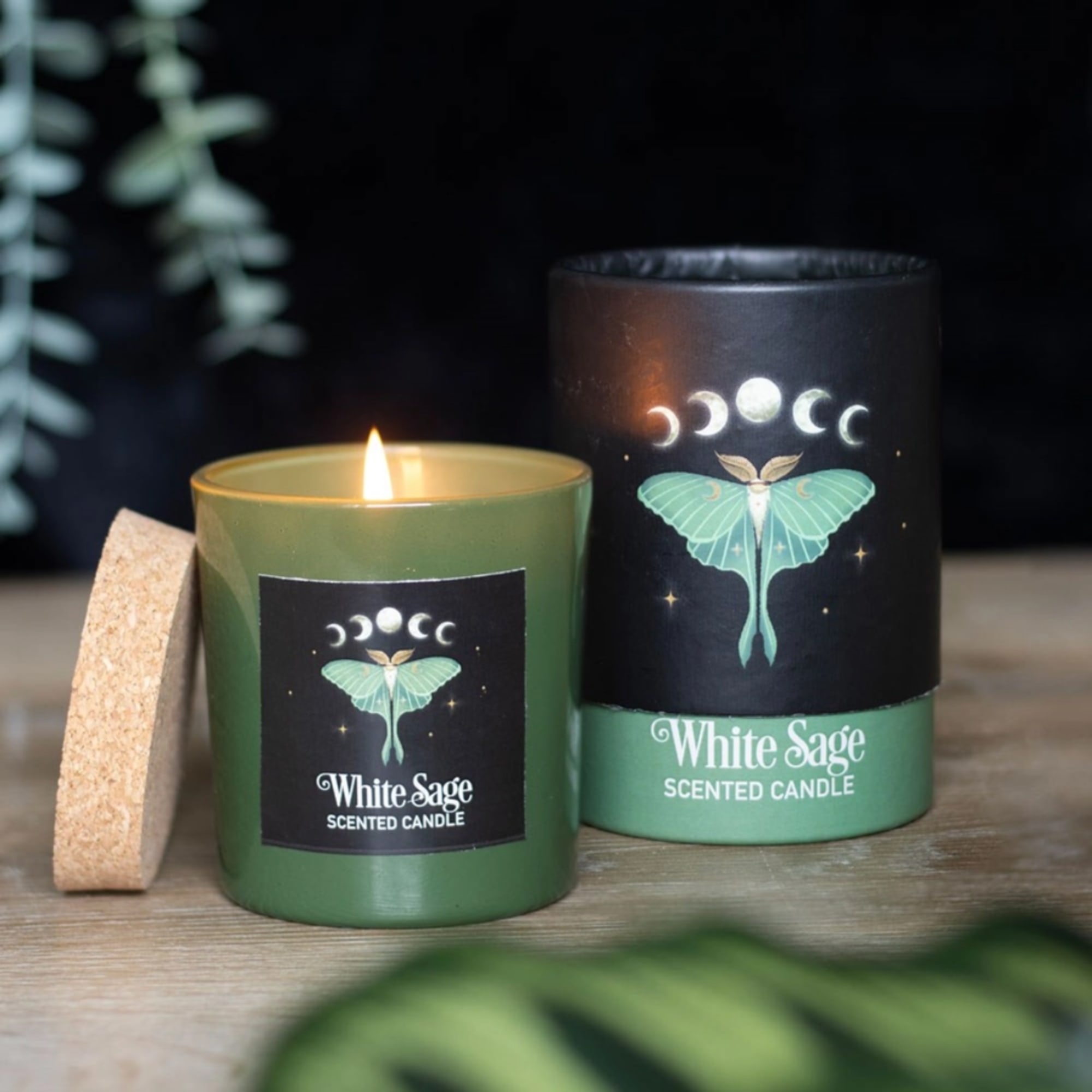 Two white sage scented candles in green containers, one lit