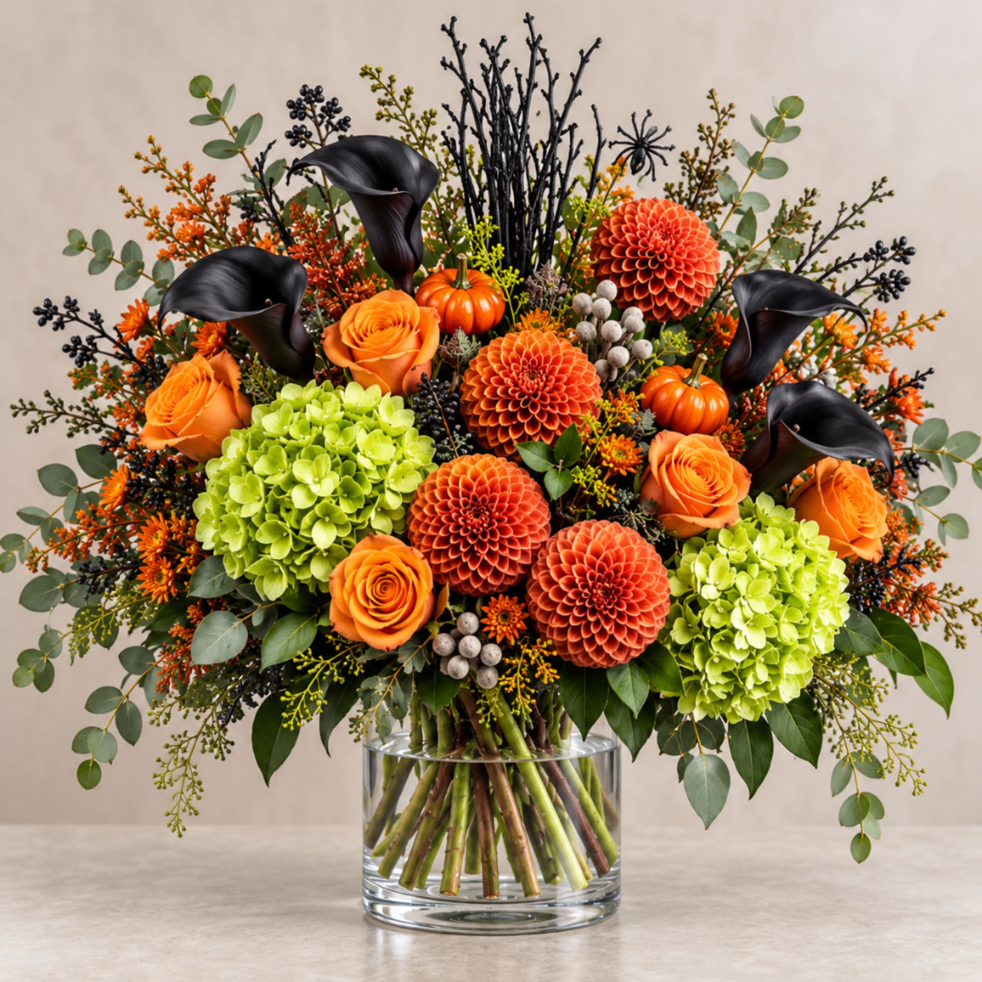 Orange and black floral arrangement in a clear glass vase with green hydrangeas
