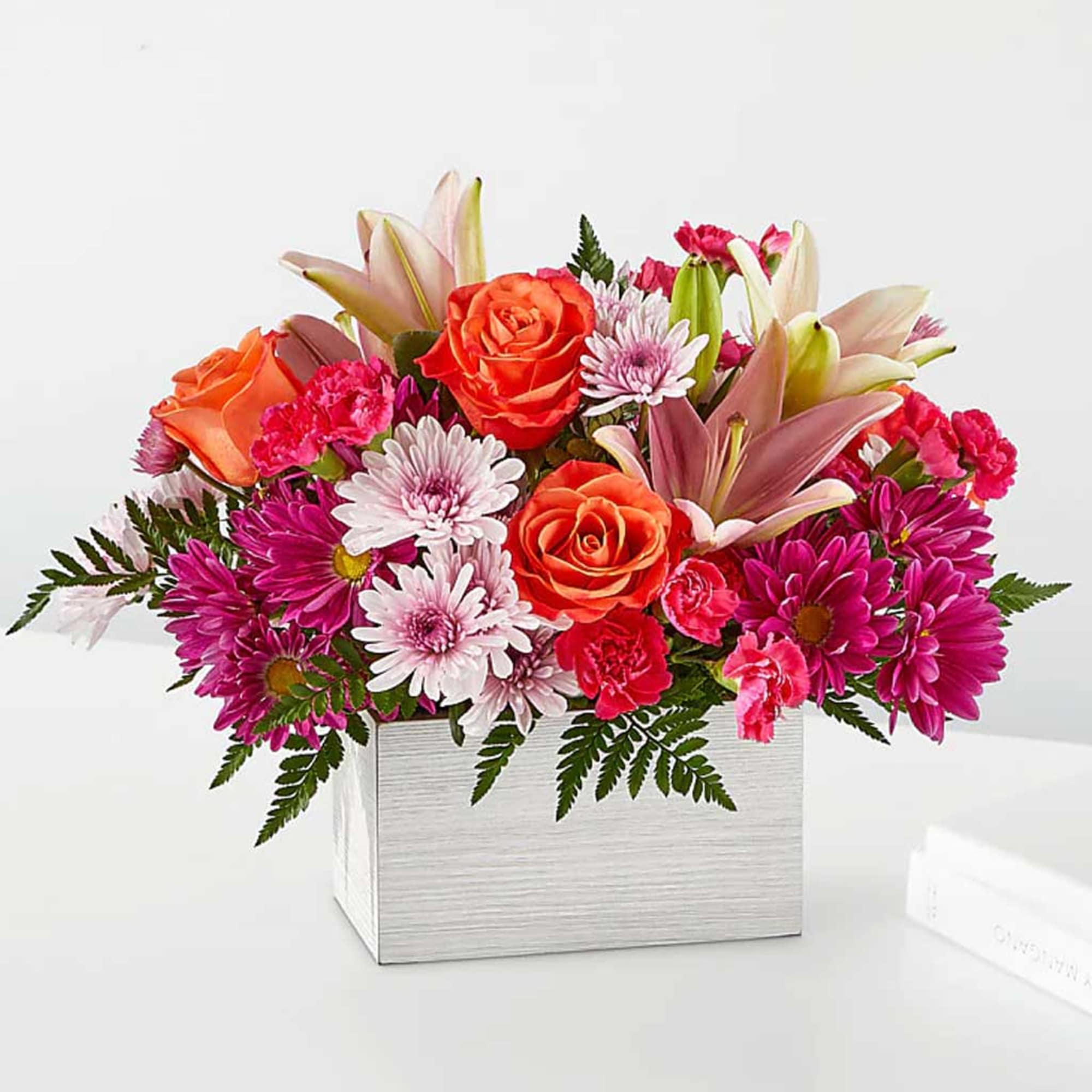 Mixed bouquet of roses, lilies, and daisies in a white box