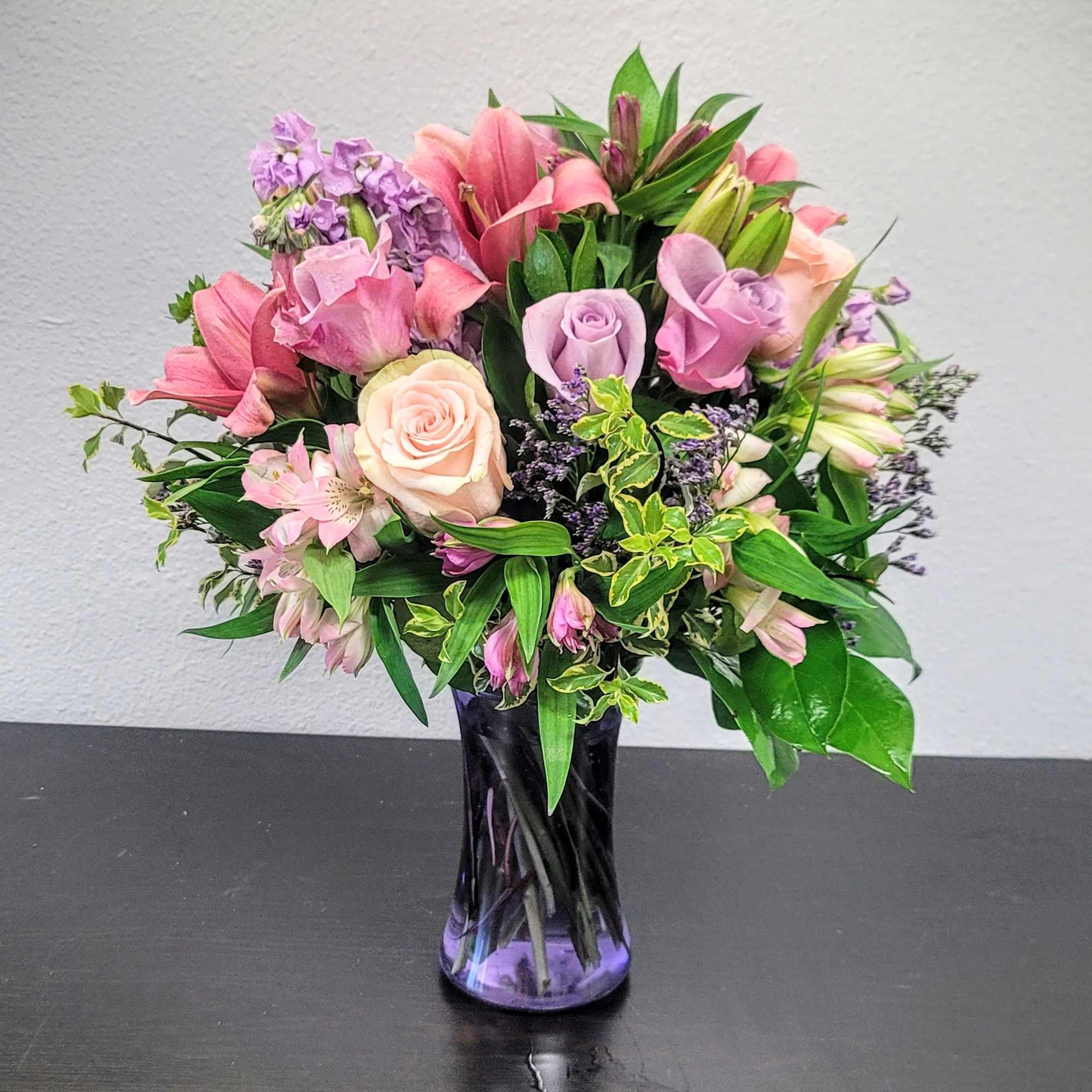 Pink and lavender mixed bouquet in a purple glass vase