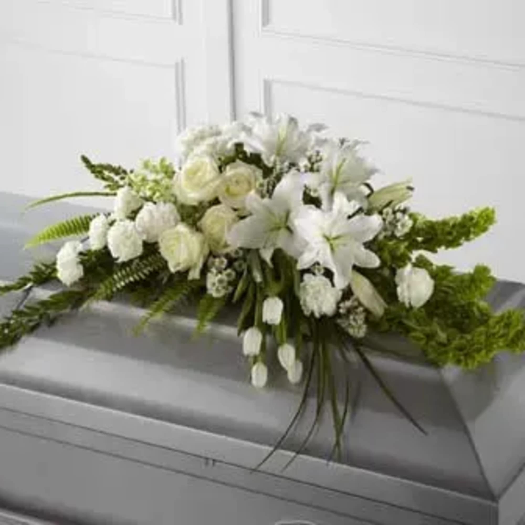 White floral casket spray with lilies and roses
