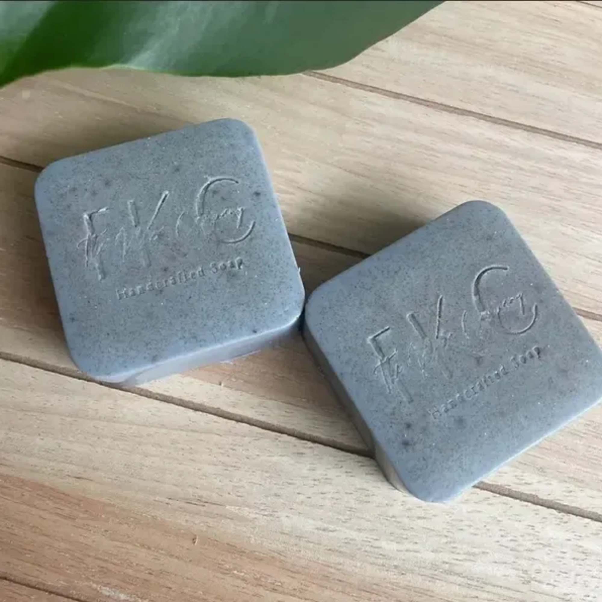 Two gray soap bars on a wooden surface