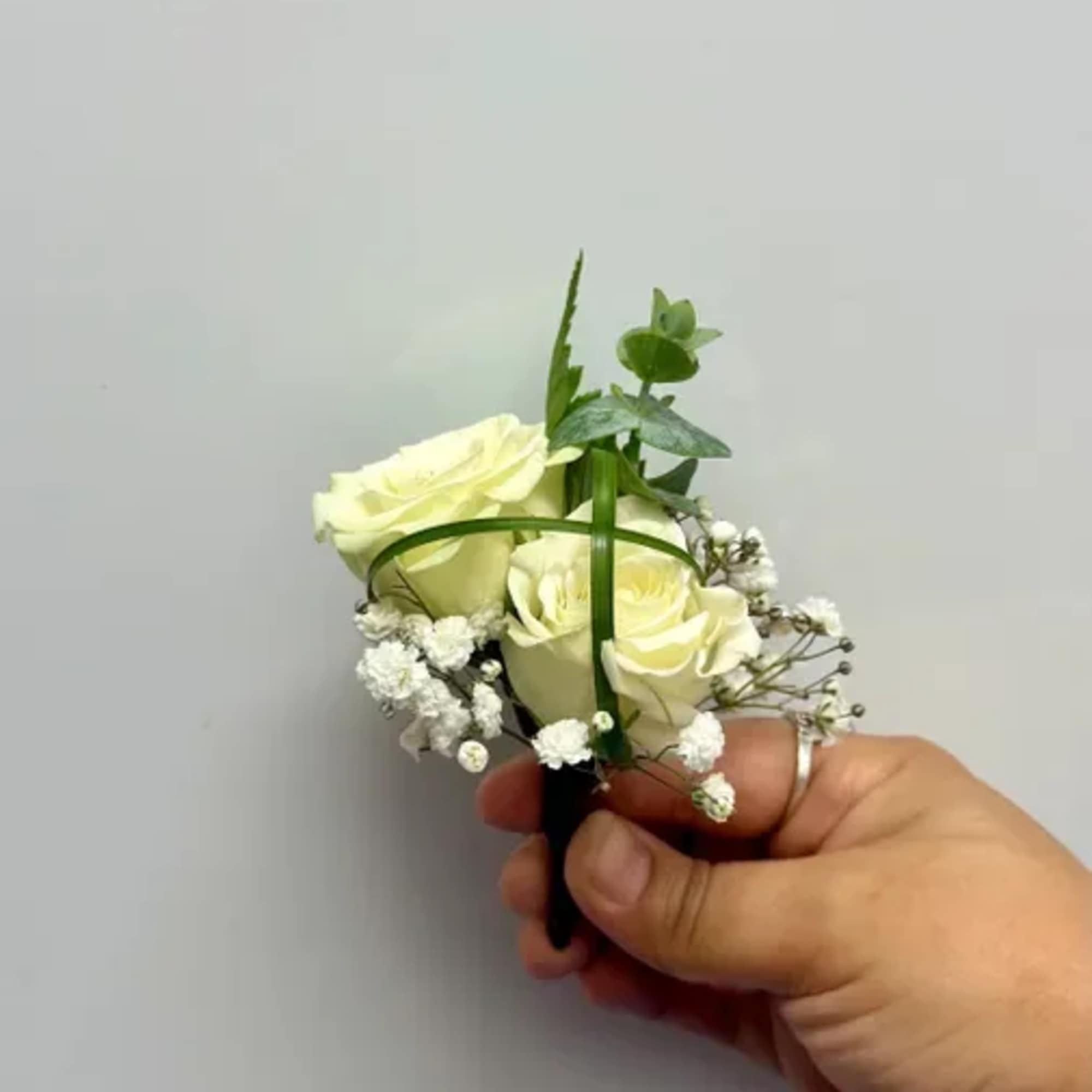 Small white rose boutonniere with baby's breath and greenery