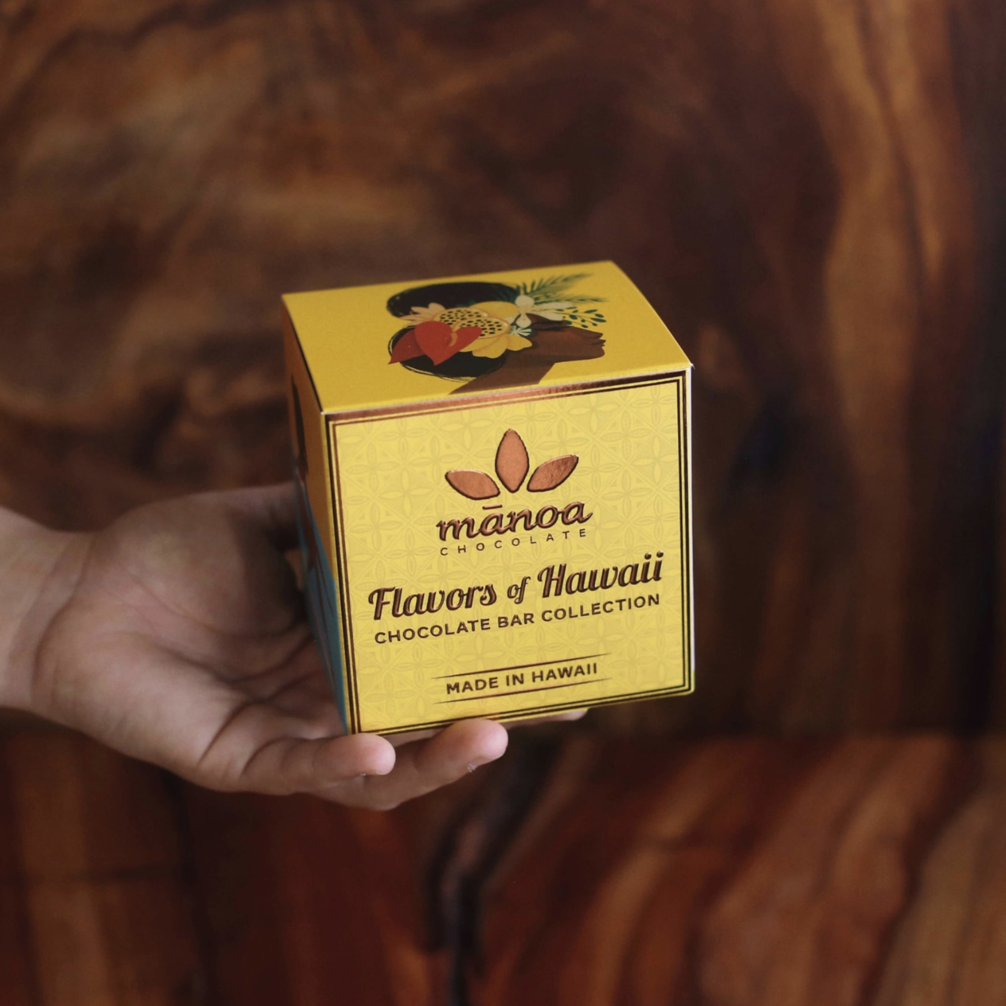 Hand holding a yellow box of Hawaiian chocolate bars