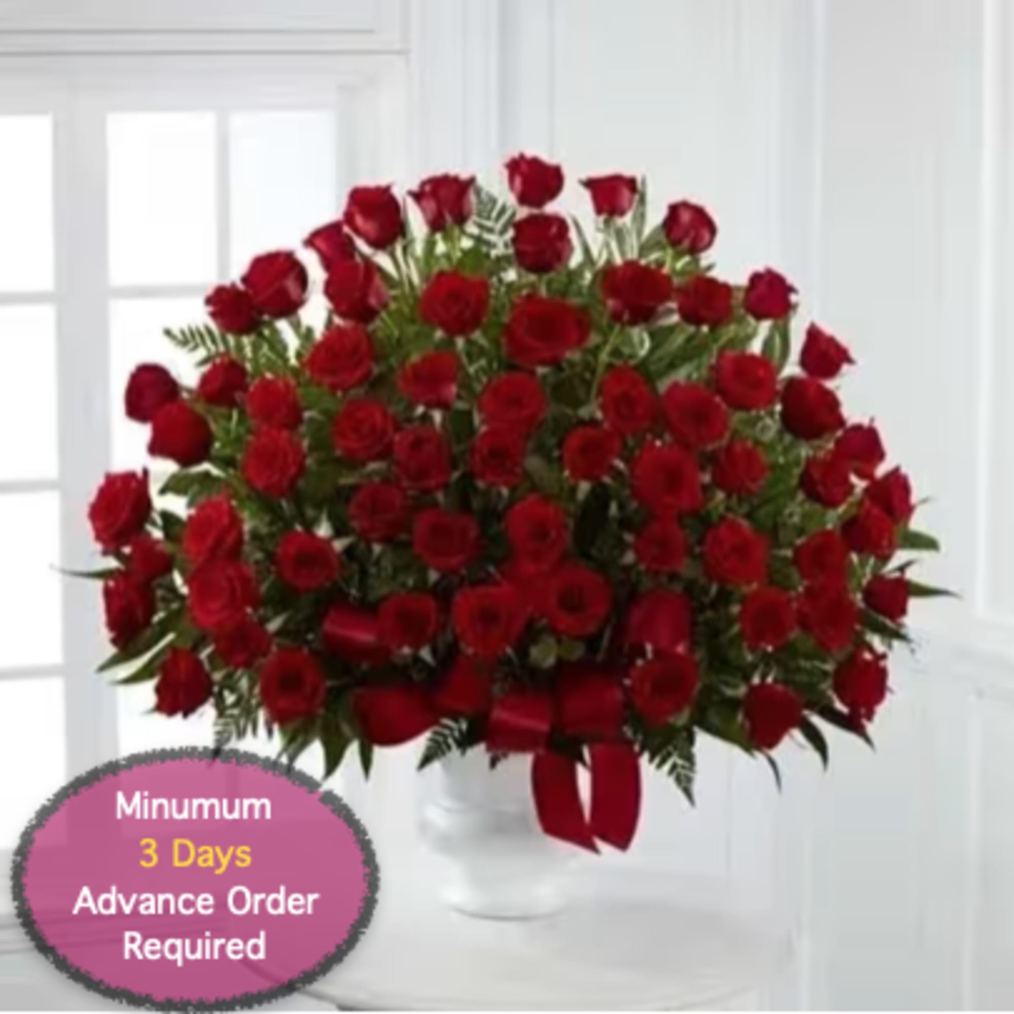 Large bouquet of red roses in a white vase with a red ribbon