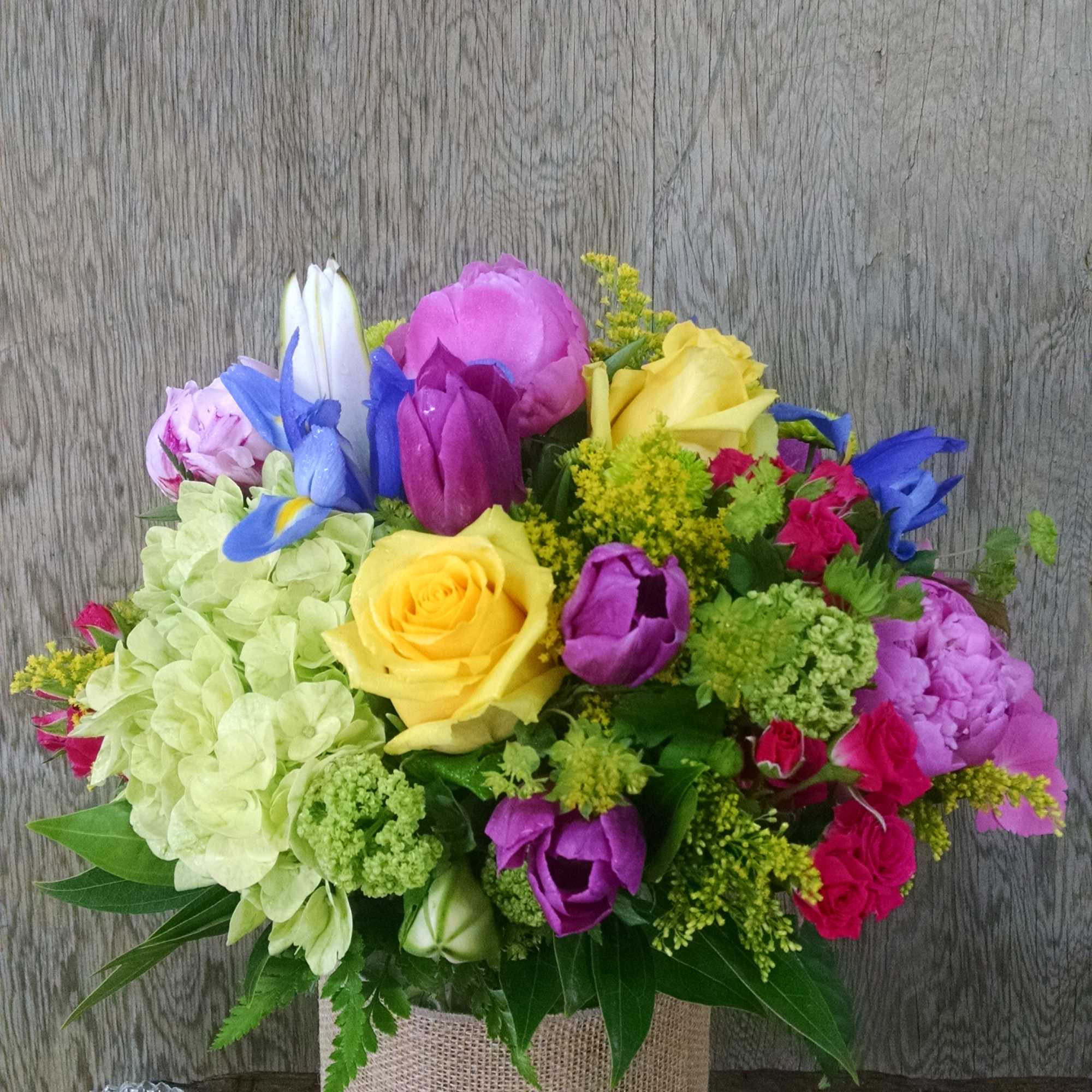 Colorful bouquet in a glass vase wrapped with burlap