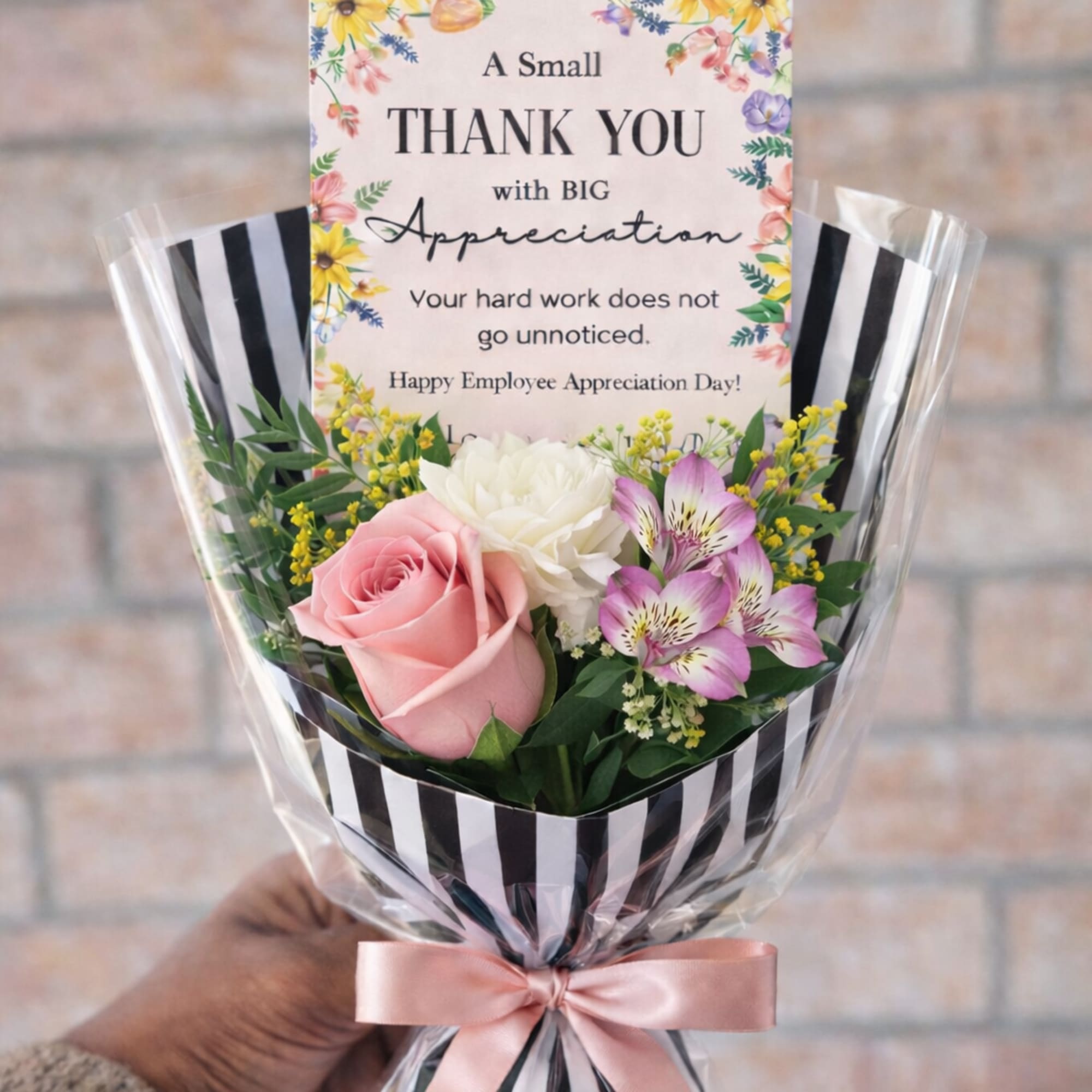 Small thank-you bouquet with pink rose, white carnation, and purple alstroemeria in striped wrap with card.