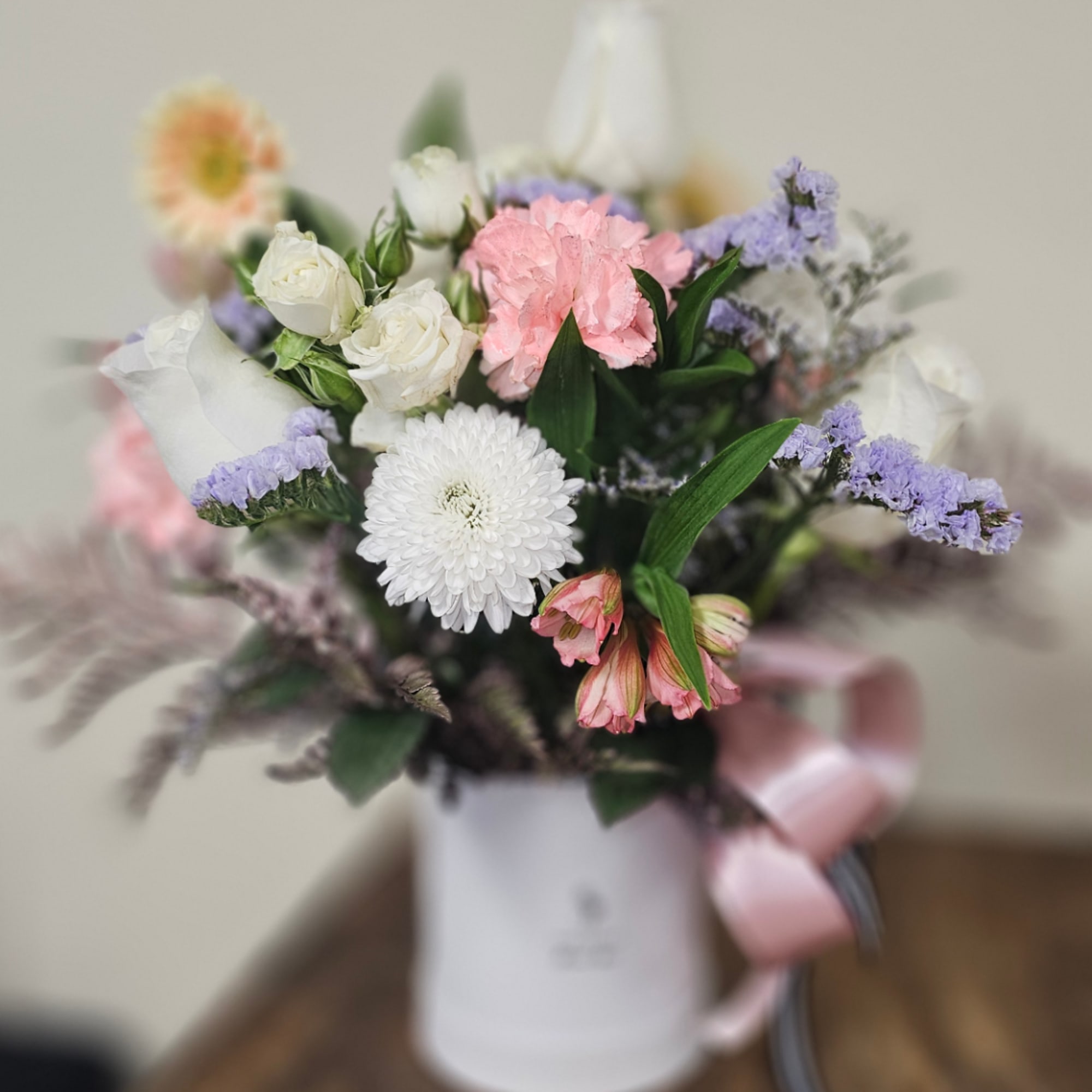 Mixed bouquet of white, pink, and lavender flowers in a white vase