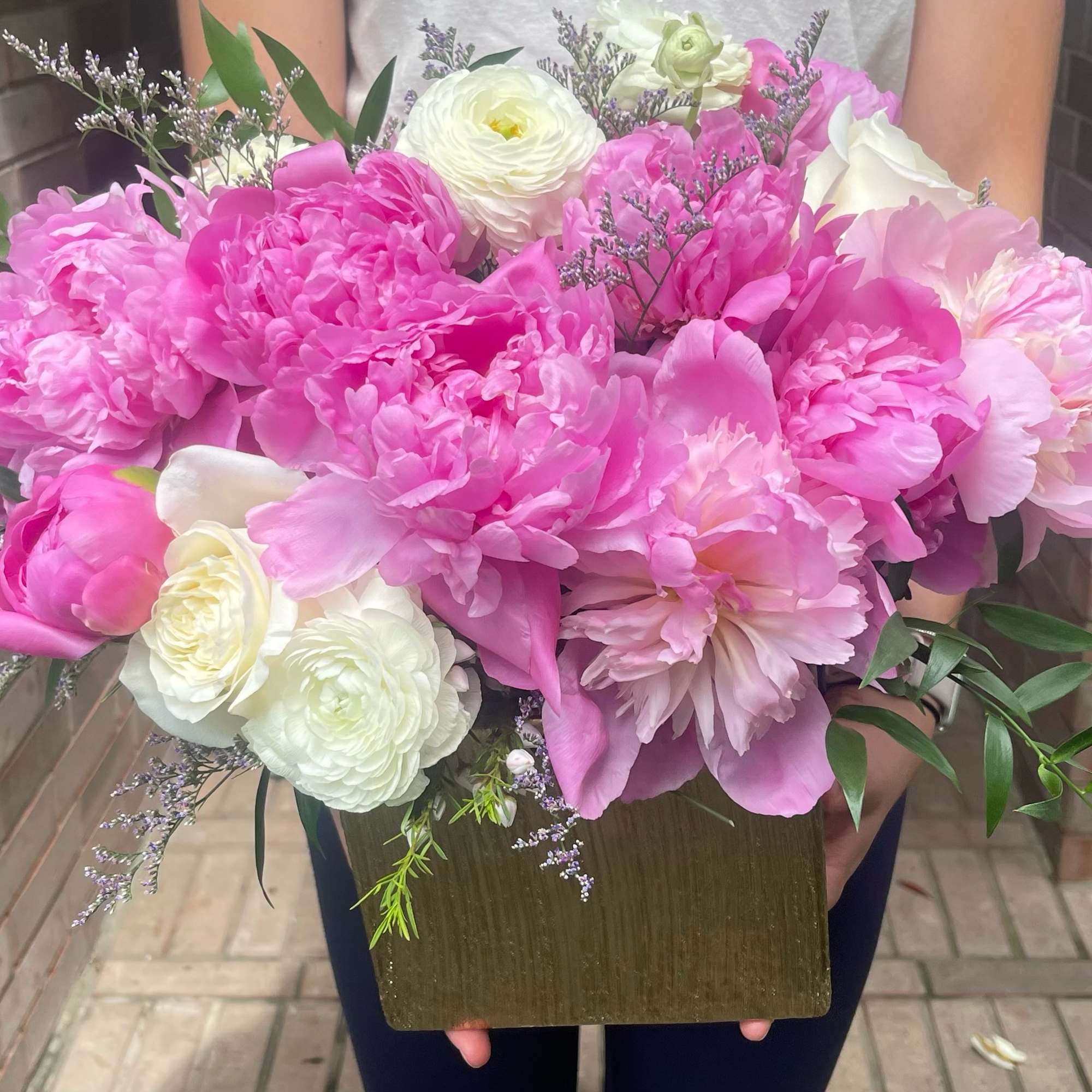Large pink and white floral arrangement in a gold box