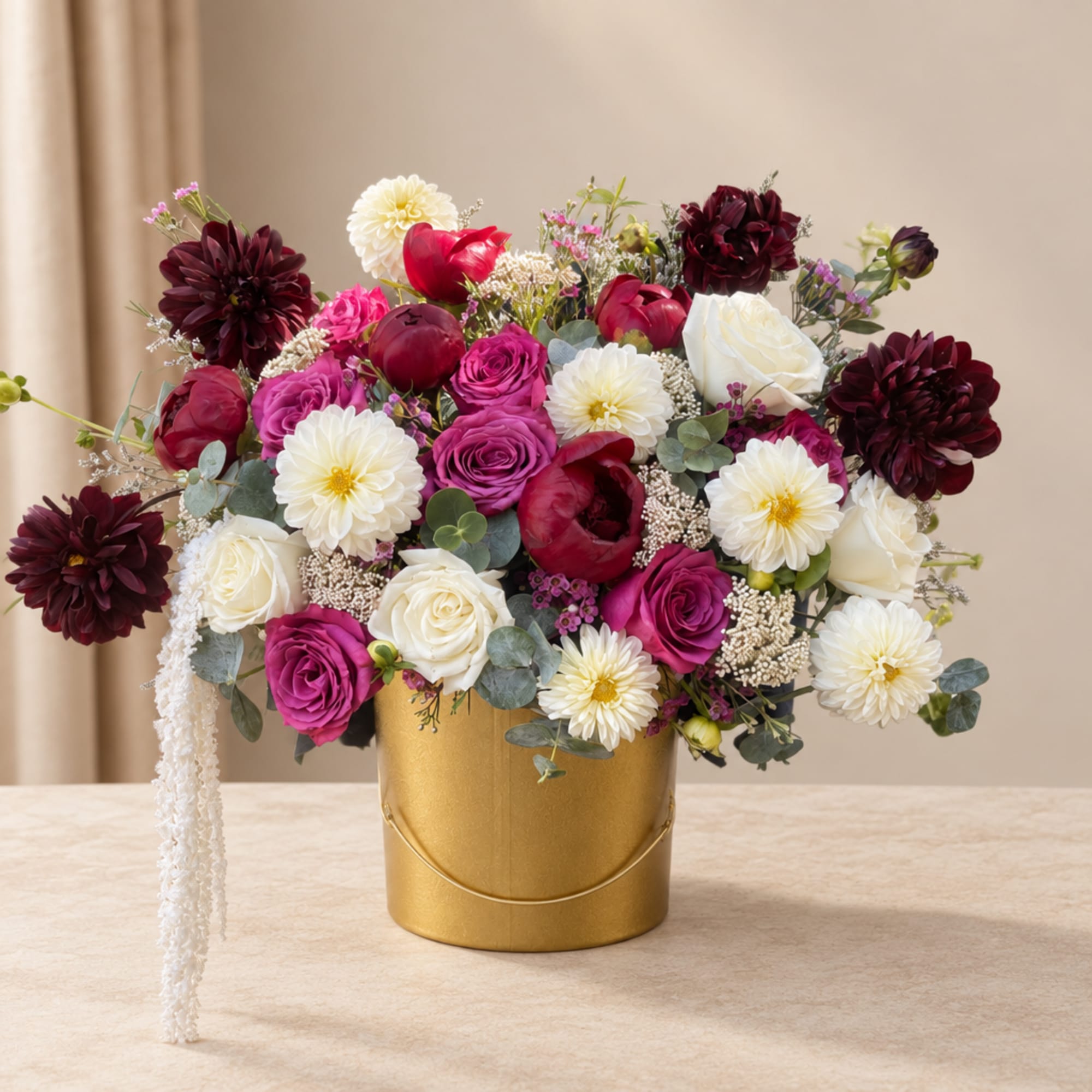 Mixed pink, white, and burgundy flowers arranged in a gold bucket
