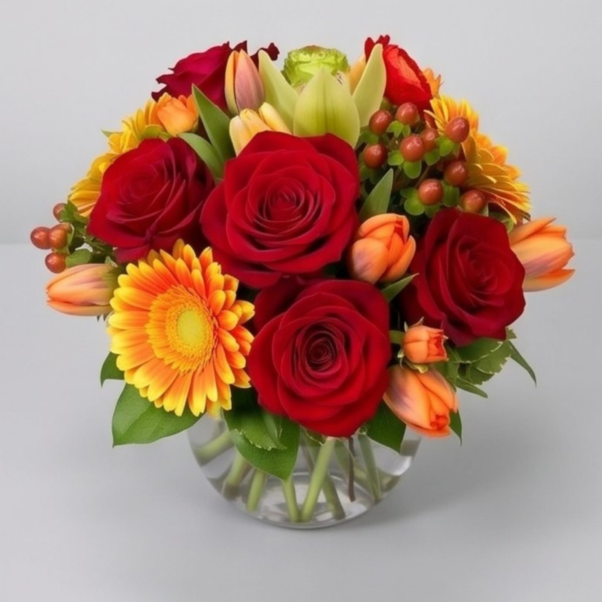 Bouquet of red roses and orange-yellow daisies in a clear glass vase