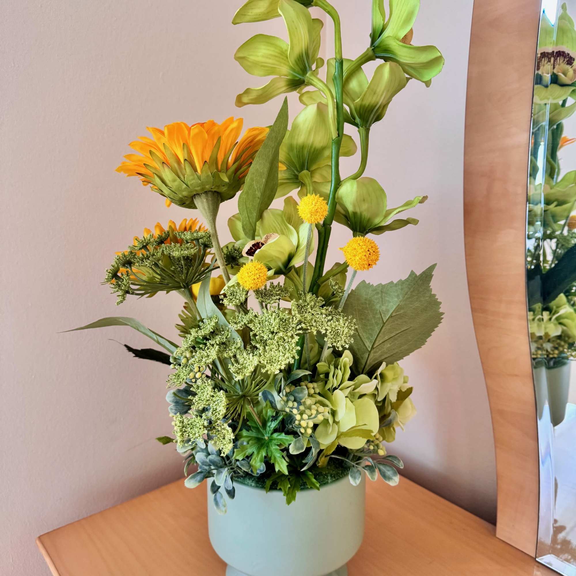 Tall floral arrangement in a pale blue vase with green and yellow blooms