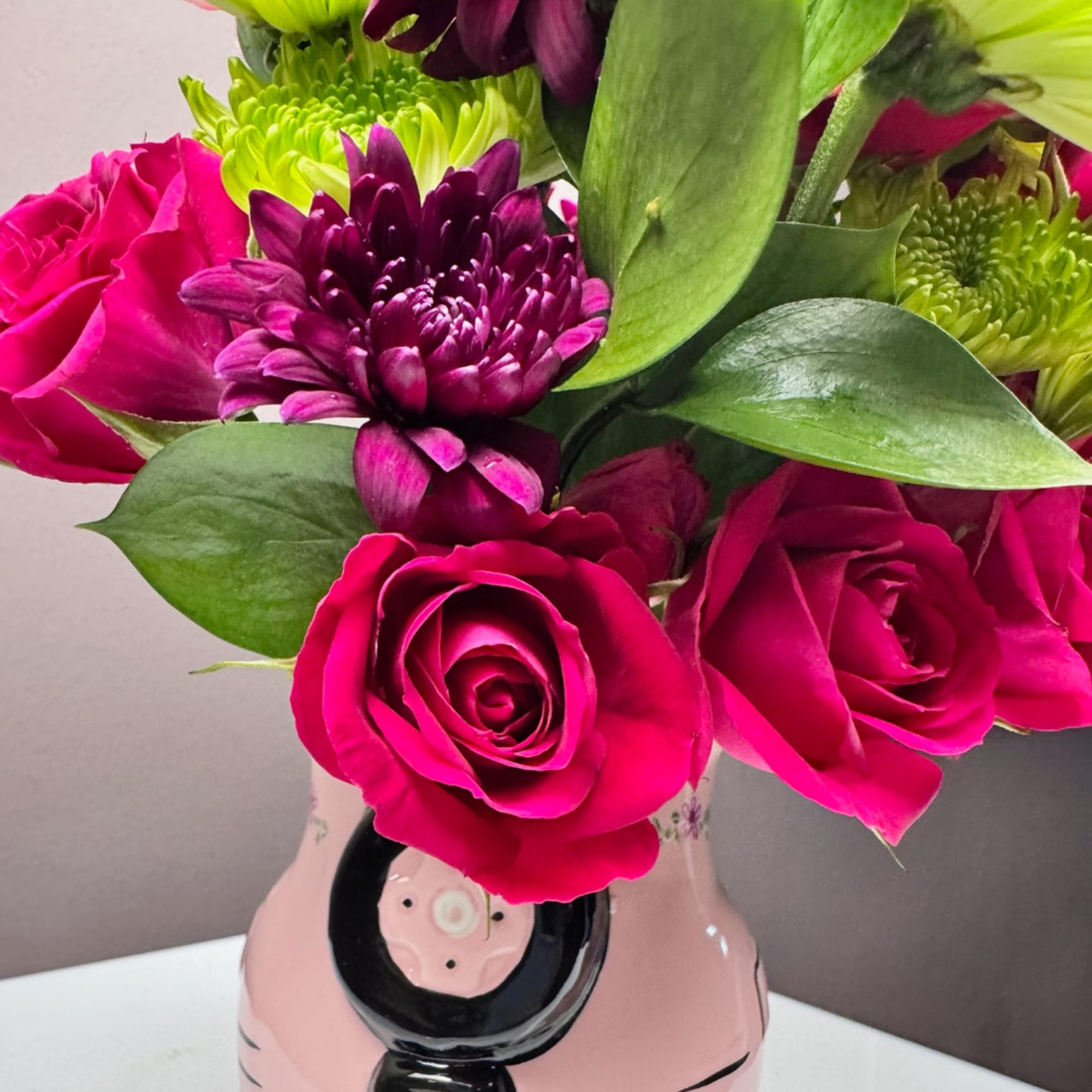 Pink roses and purple chrysanthemums in a pink ceramic vase