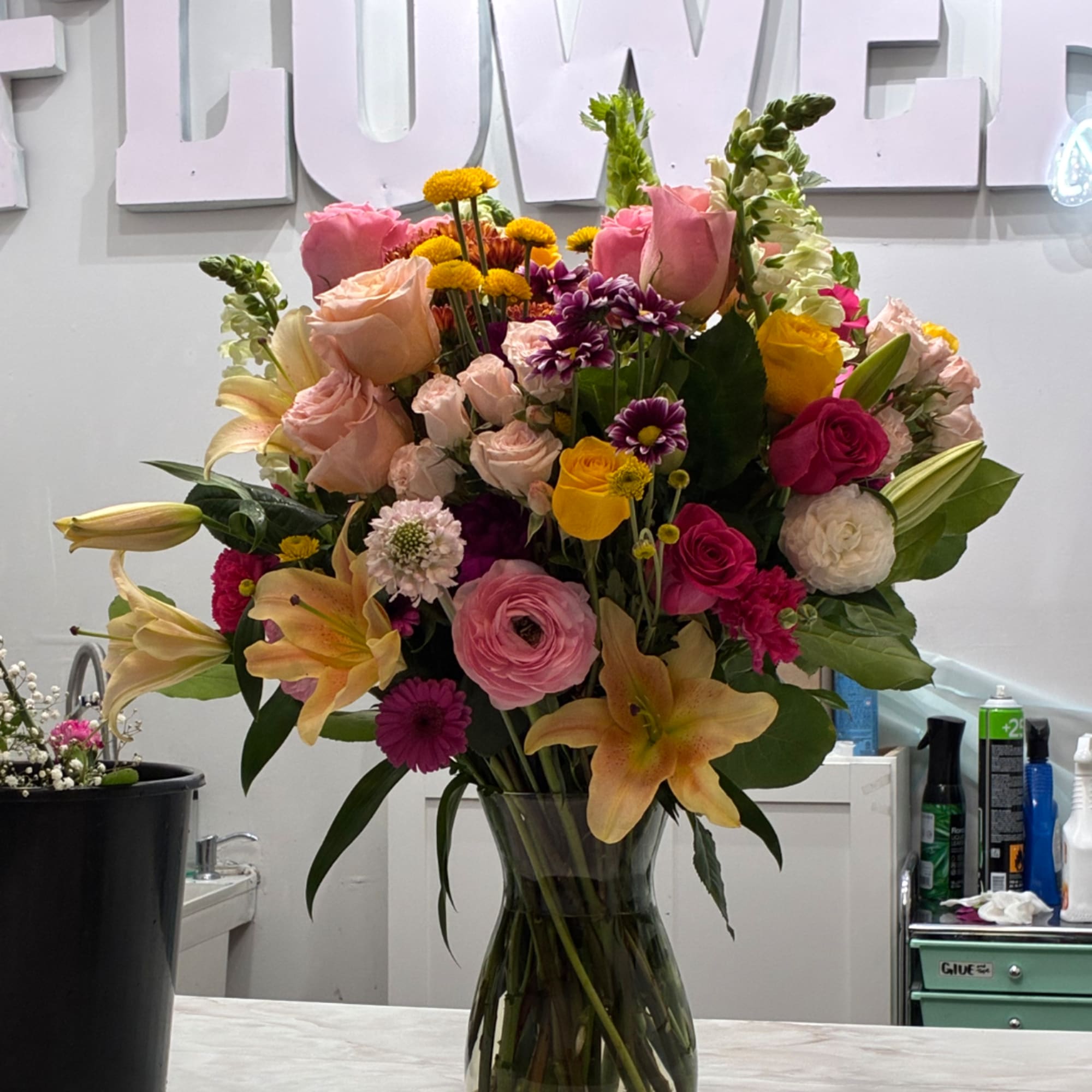 Mixed bouquet of pink, yellow, and white flowers in a clear glass vase