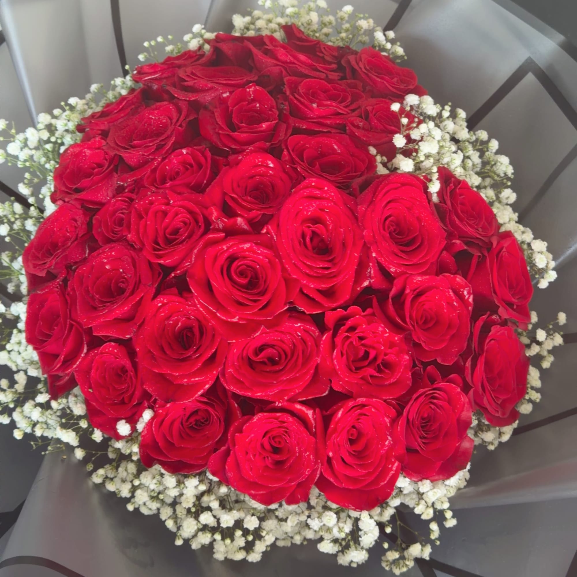 Bouquet of red roses with white baby's breath in gray wrapping