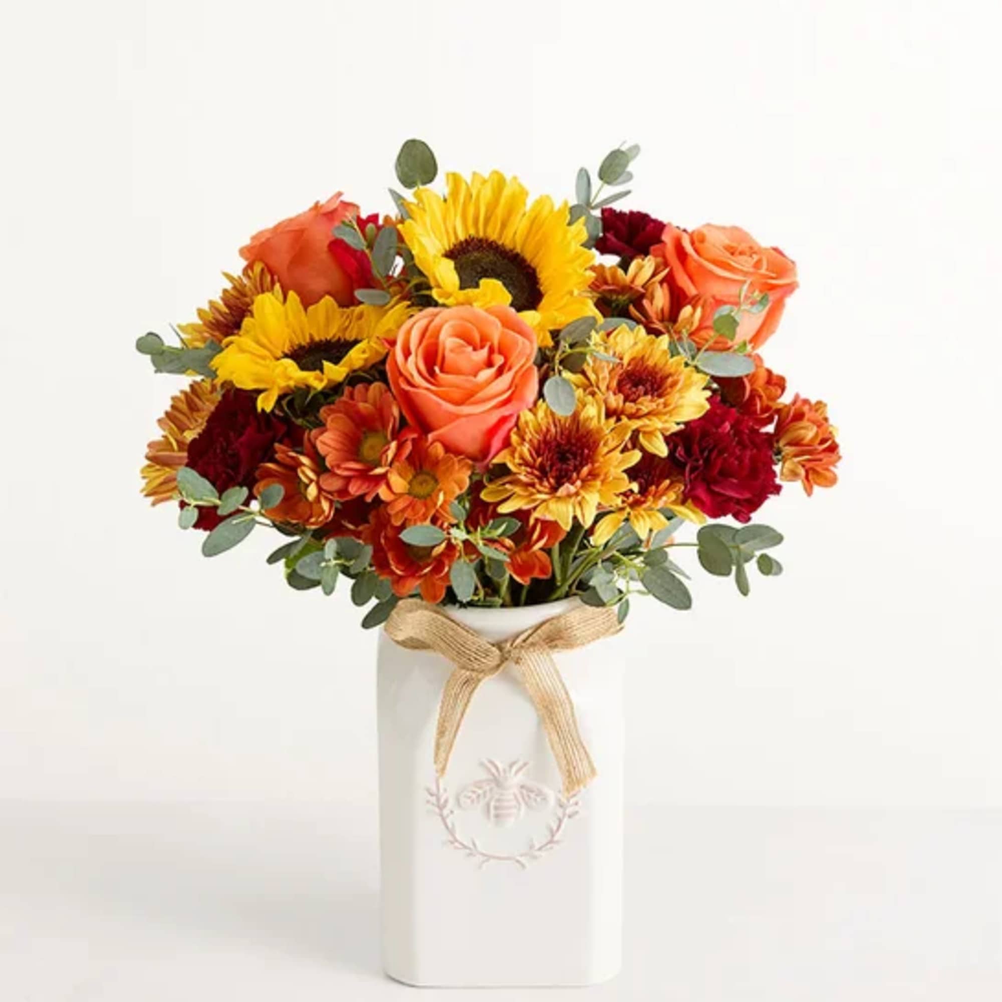 Bouquet of sunflowers, roses, and mums in a white vase with a ribbon