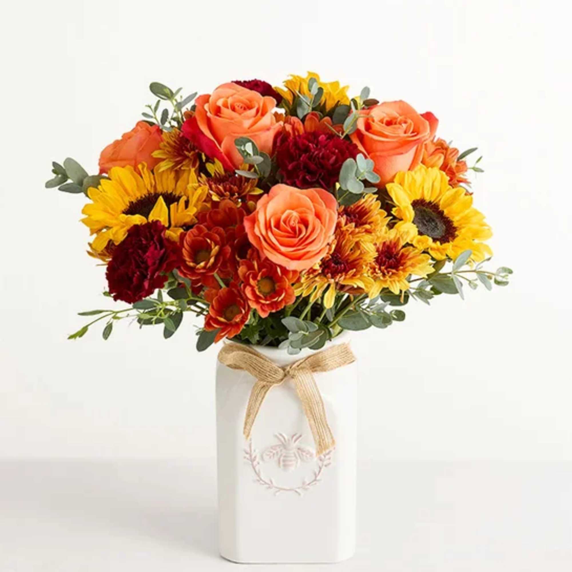 Bouquet of orange roses and sunflowers in a white vase