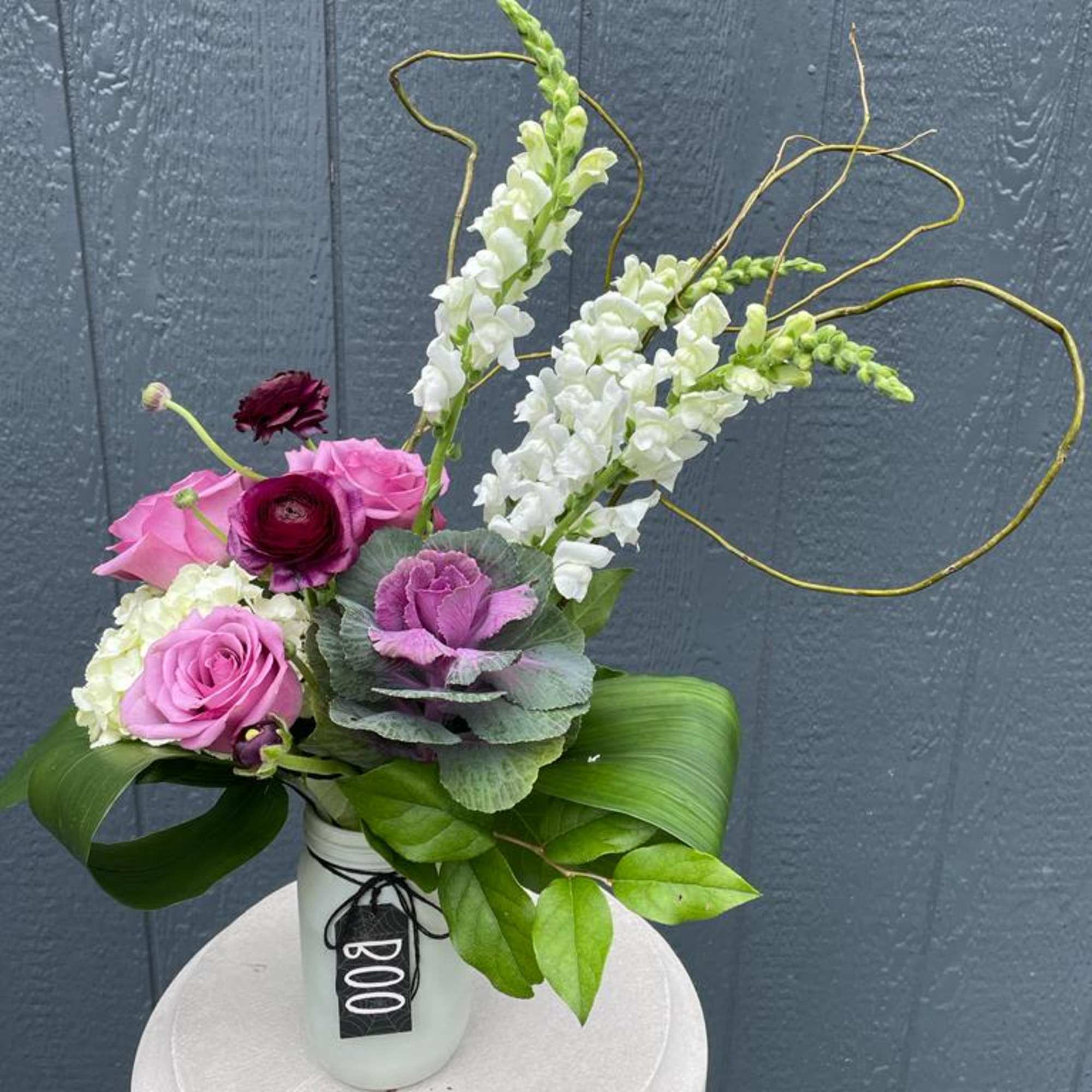 Pink and white floral arrangement in a white vase with looping branches