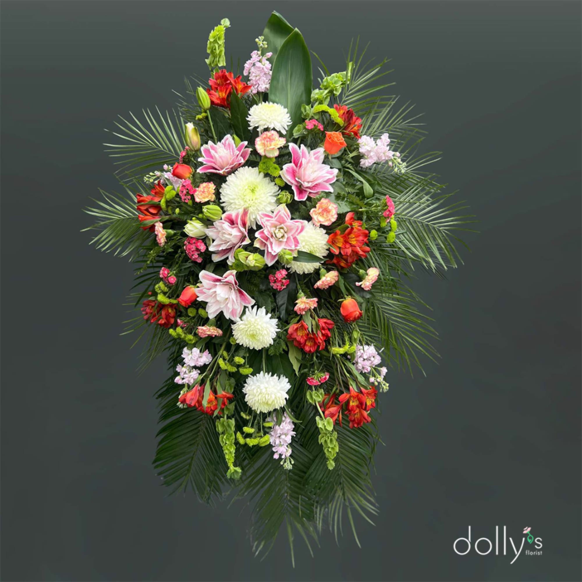 Standing floral spray with pink, white, and red blooms on a dark background