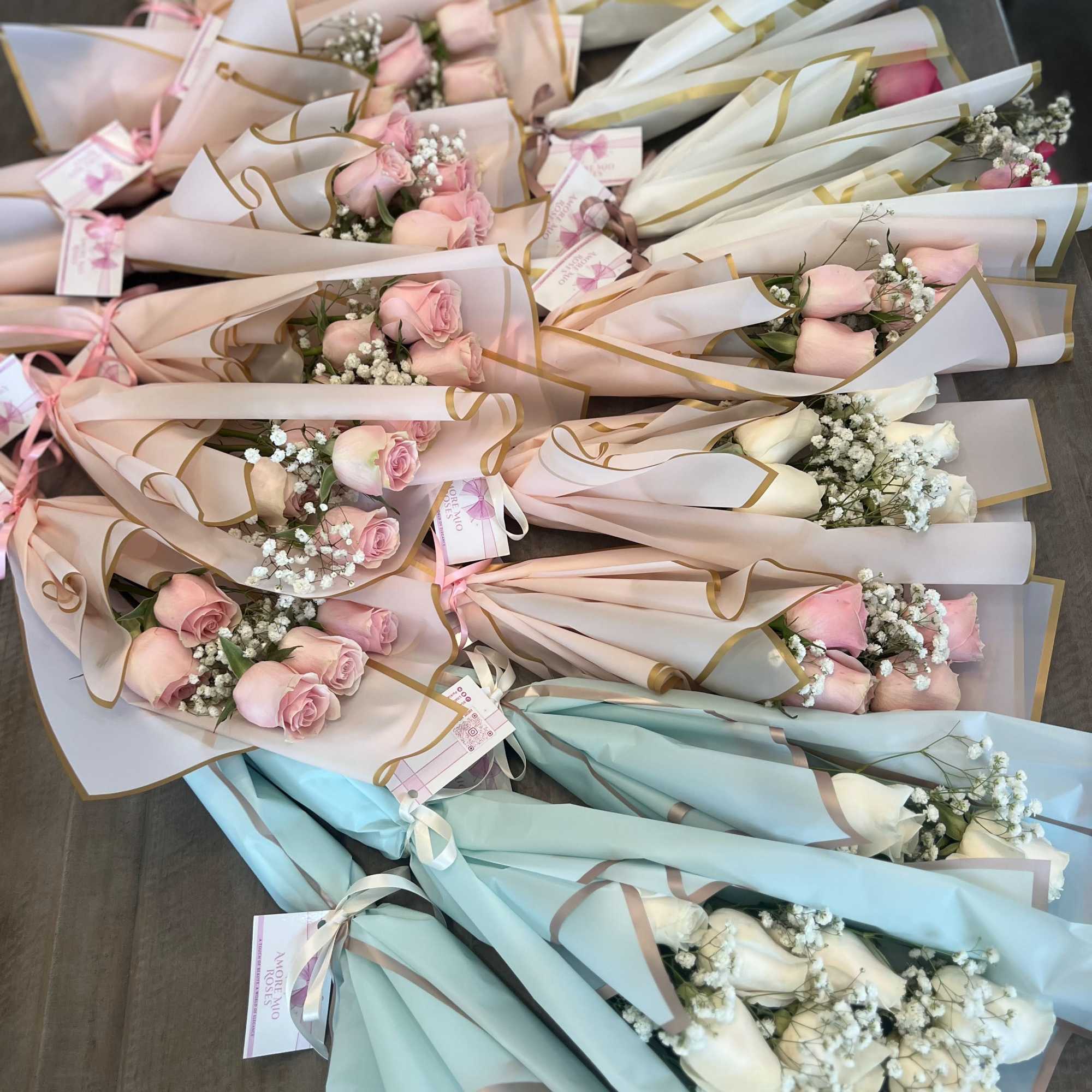 Wrapped bouquets of pink and white roses arranged in pastel paper
