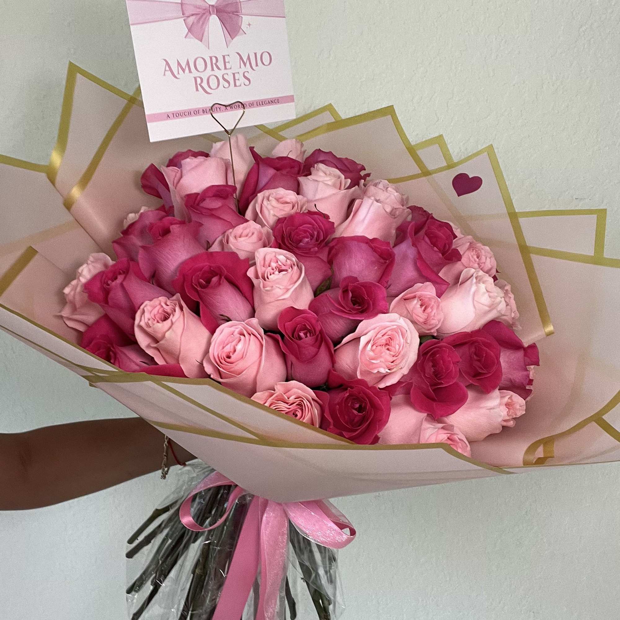 Bouquet of pink and hot pink roses wrapped in blush paper with a ribbon