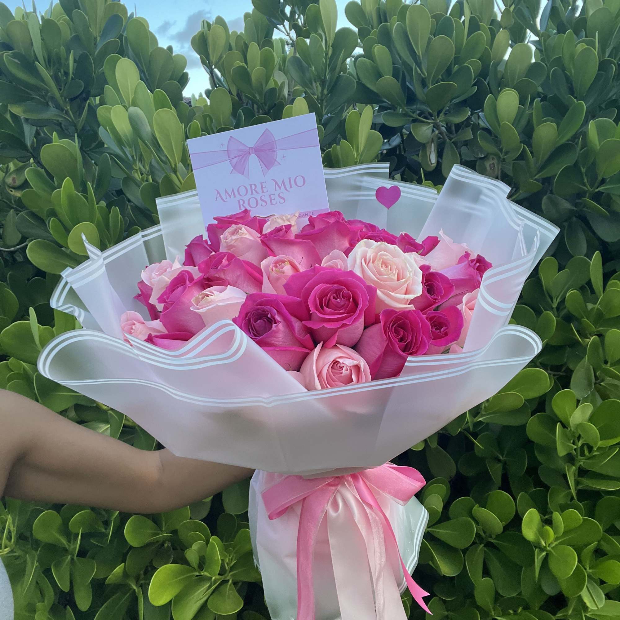 Bouquet of pink and white roses wrapped in white paper with a pink ribbon