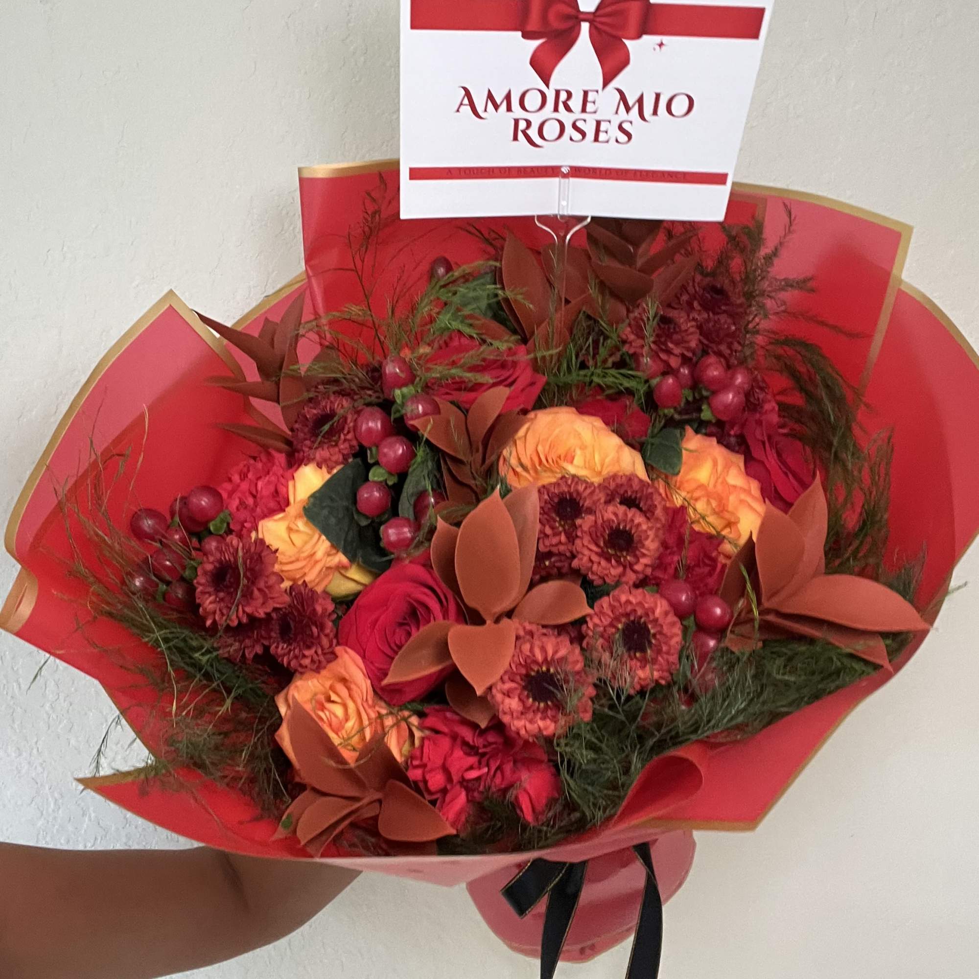 Bouquet of red and orange roses with burgundy flowers in red wrapping