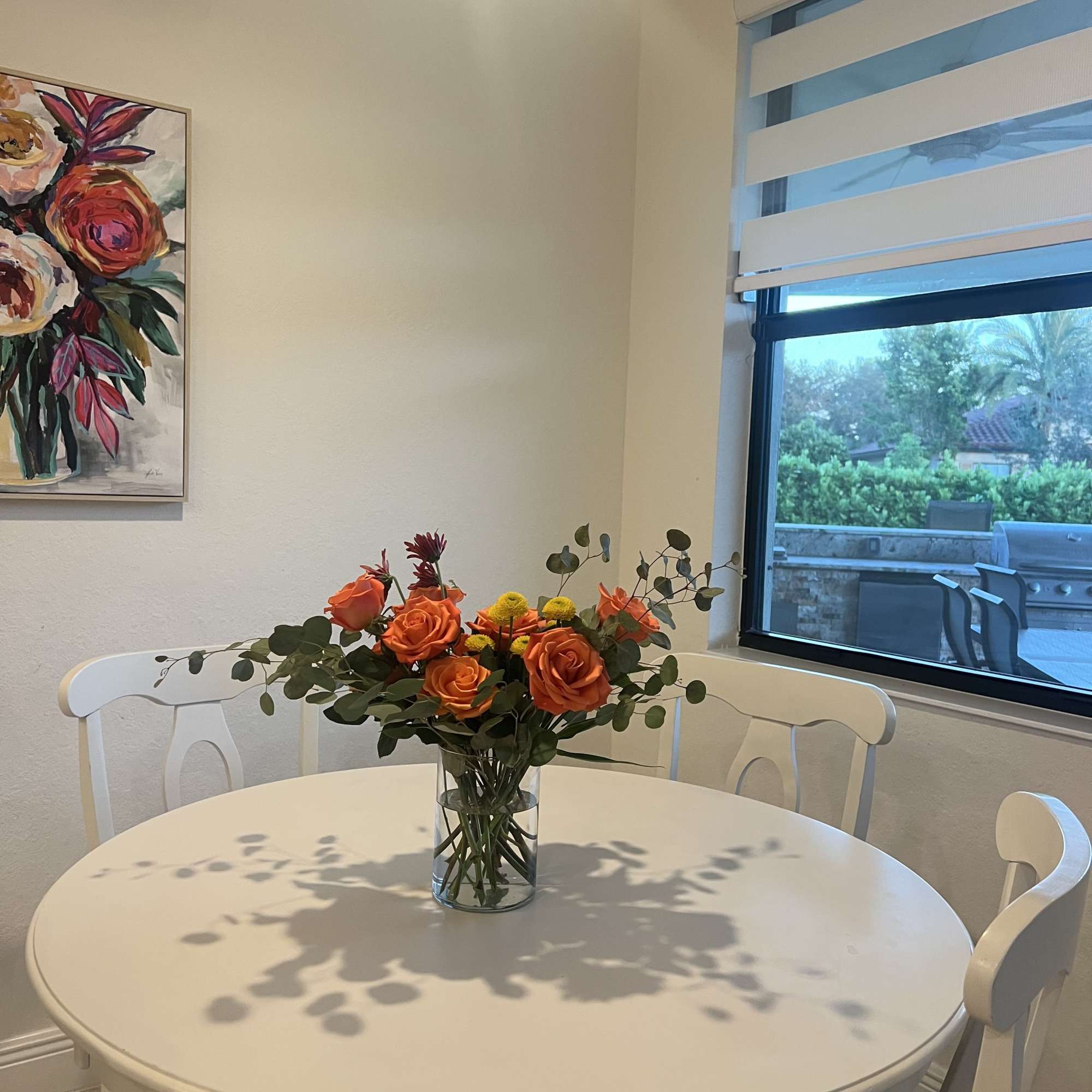 Orange roses and yellow flowers in a clear glass vase on a round white table