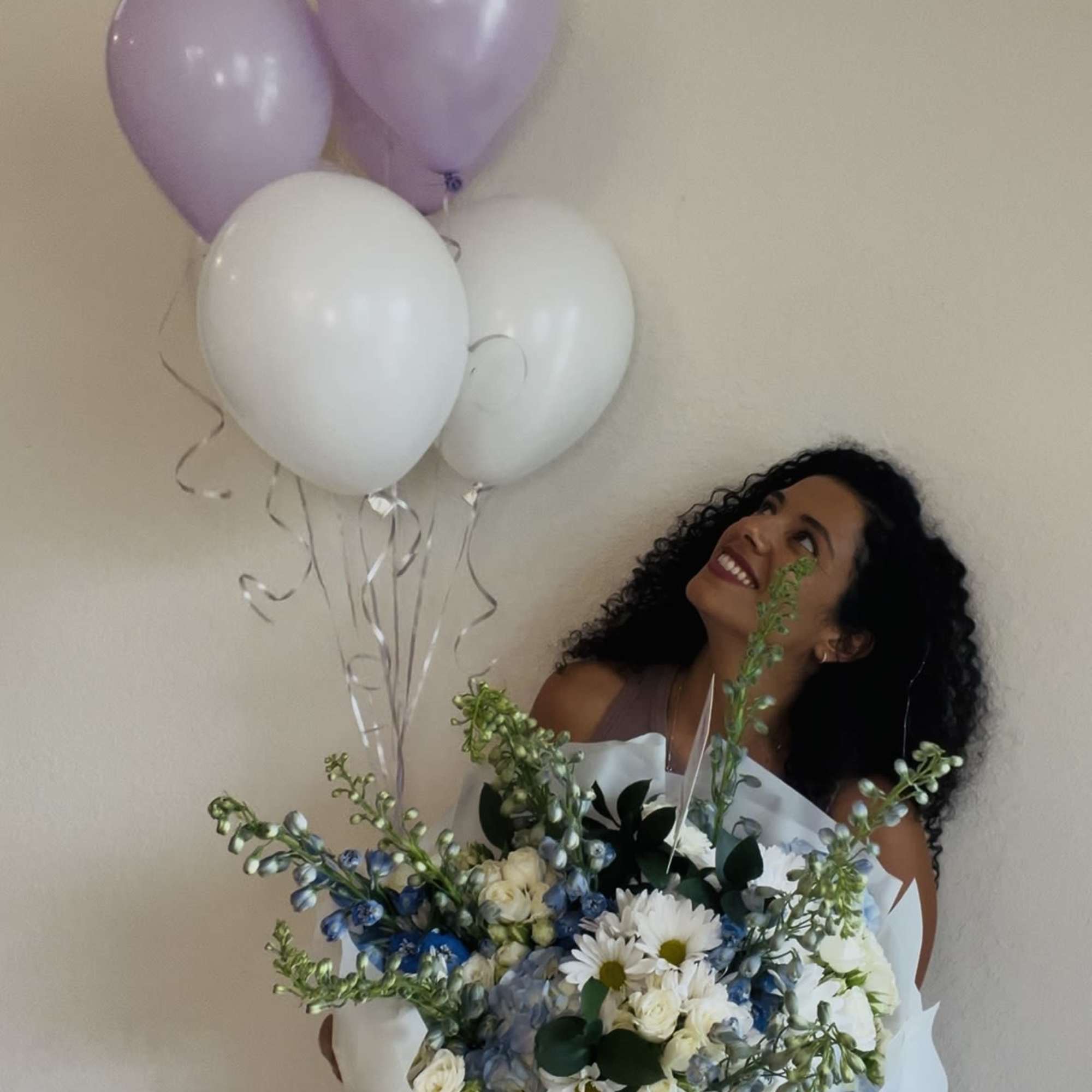 Woman holding a bouquet with pastel balloons overhead