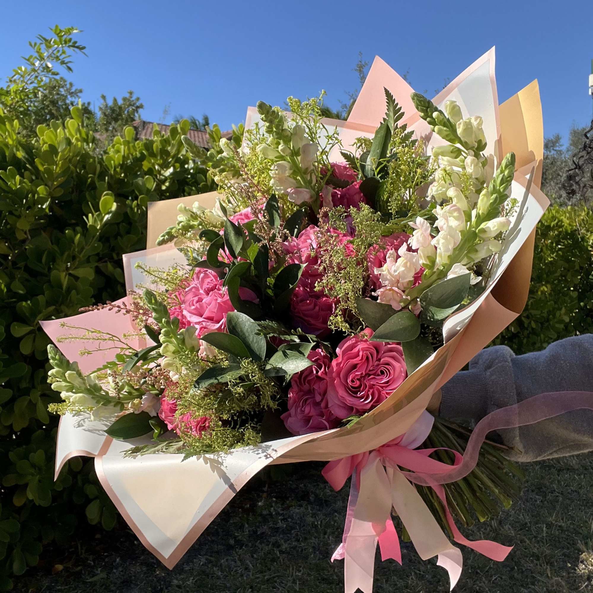 Bouquet of pink roses and white snapdragons wrapped in pastel paper