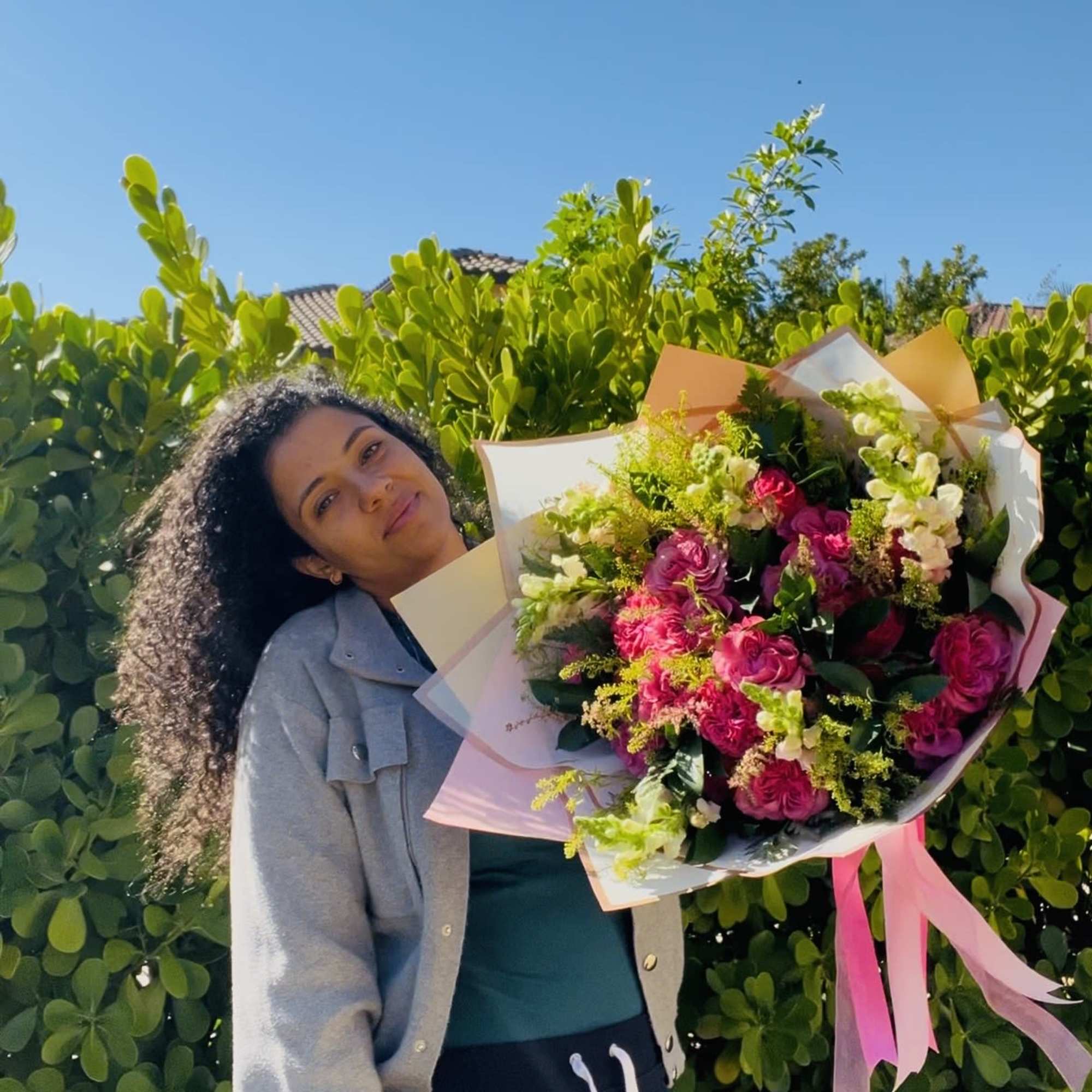 Woman holding a large bouquet of pink and white flowers wrapped in pastel paper