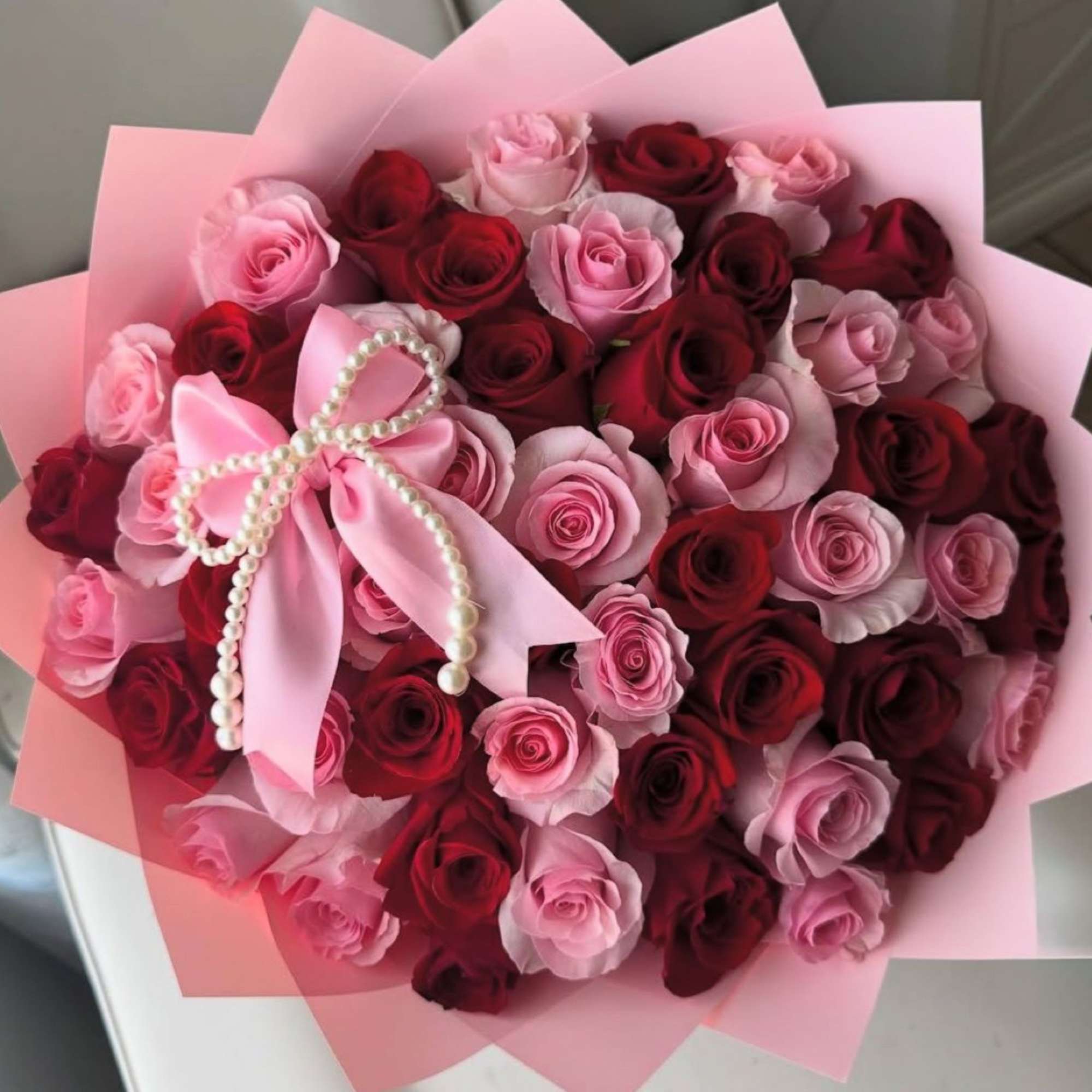 Bouquet of pink and red roses wrapped in pink paper with a satin bow