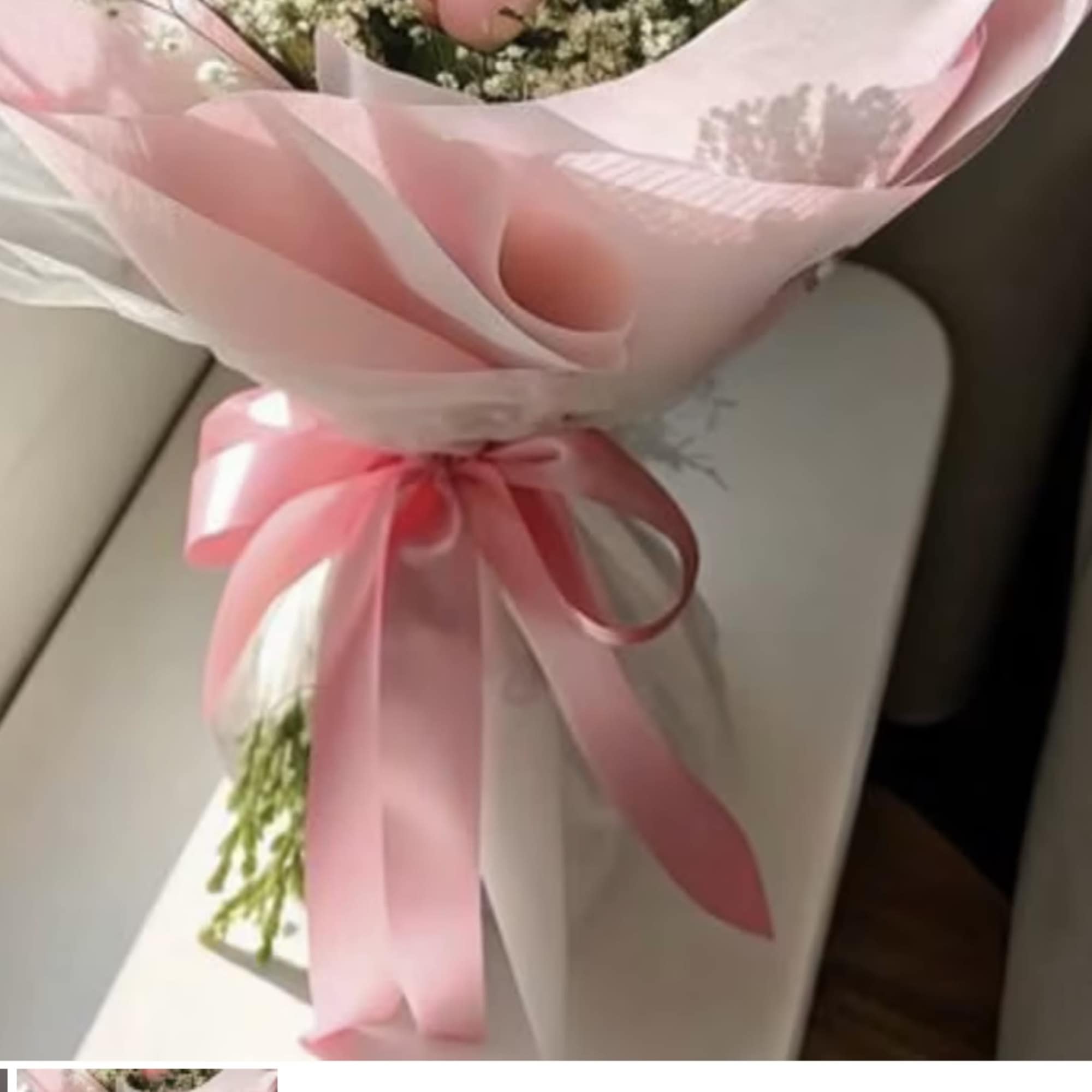 Pink-wrapped bouquet with a satin ribbon and small white flowers