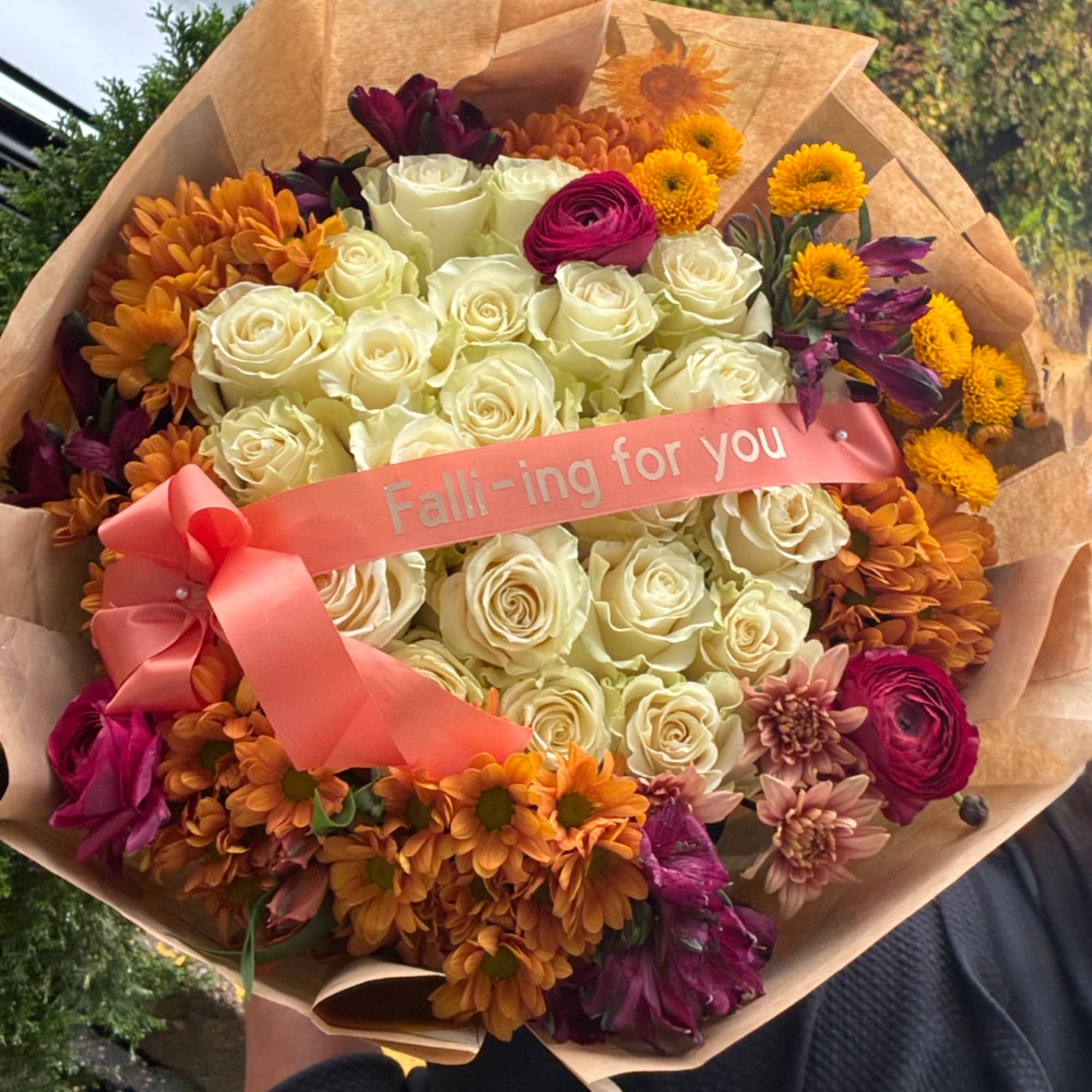 Bouquet of cream roses with orange and purple flowers, wrapped in brown paper and pink ribbon