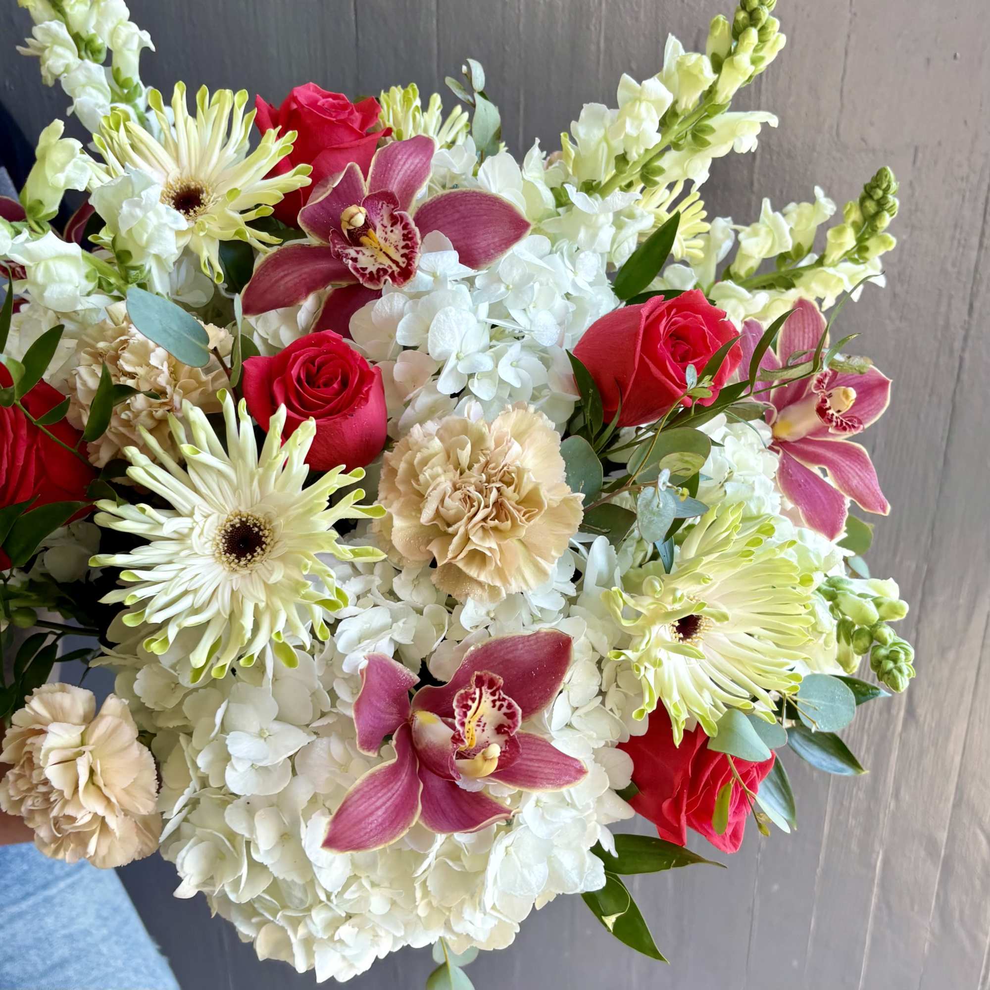 Bouquet of white hydrangeas, red roses, pink orchids, and pale carnations