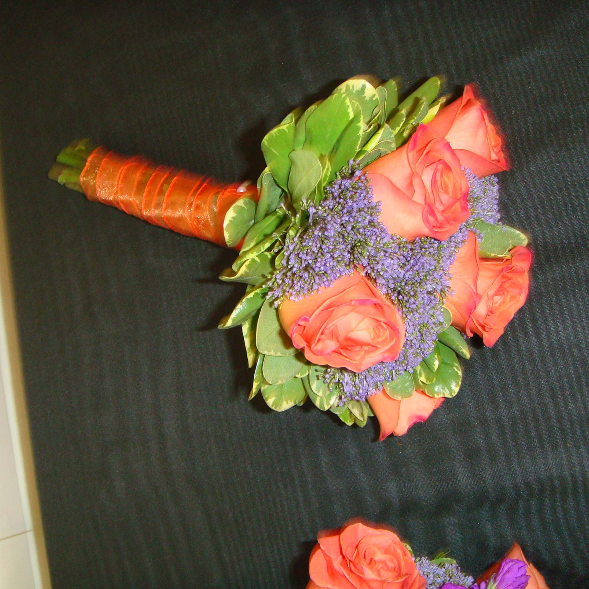 Hand-tied bouquet of coral roses with purple filler flowers