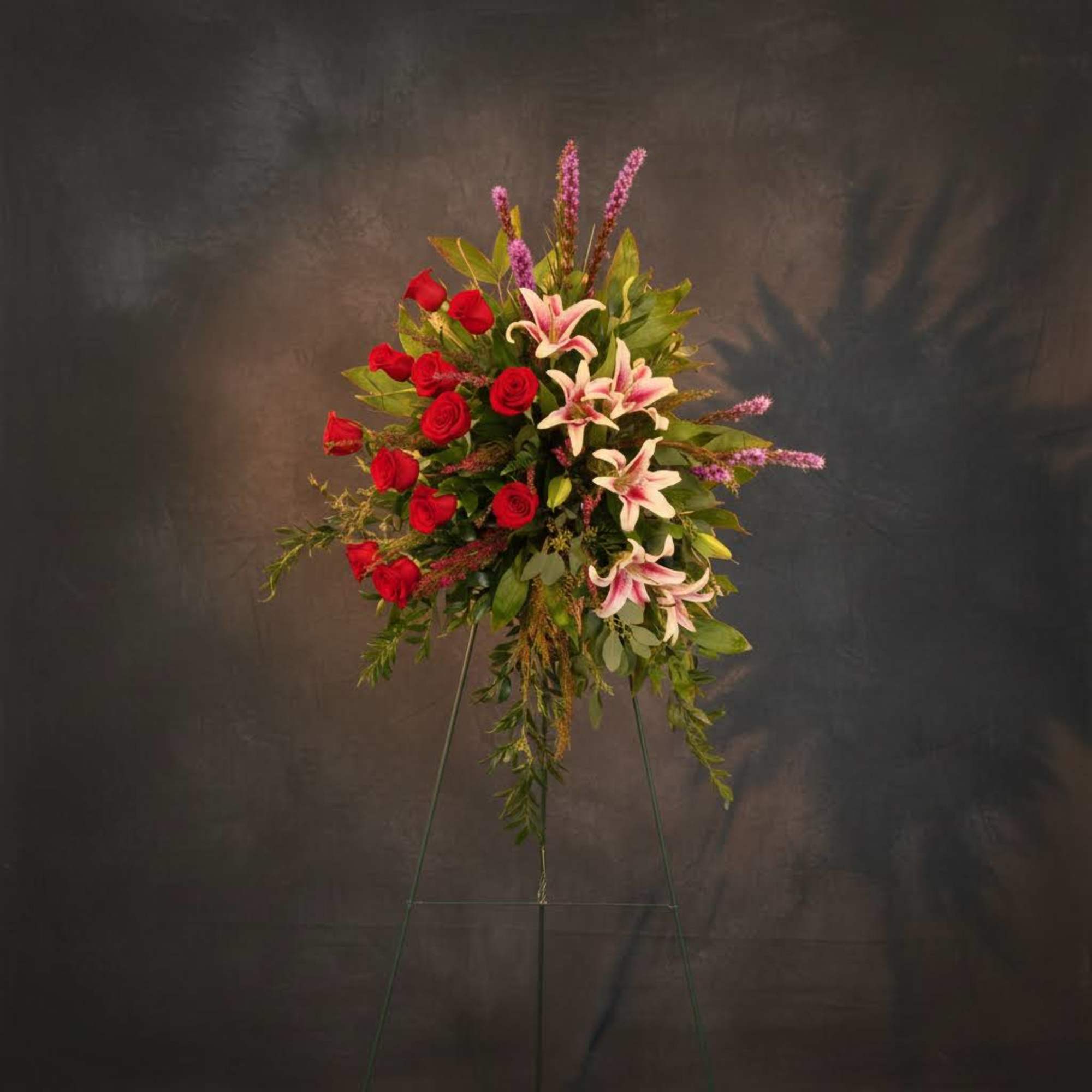 Standing floral spray with red roses and pink lilies on an easel